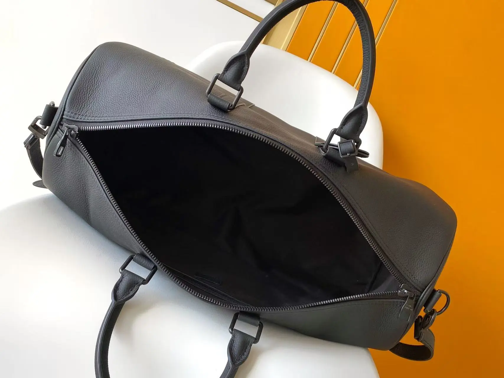 Louis Vuitton Keepall Bandouli&egrave;re 1:1 Aerogram black leather travel bag on a white chair - xiashuluxe