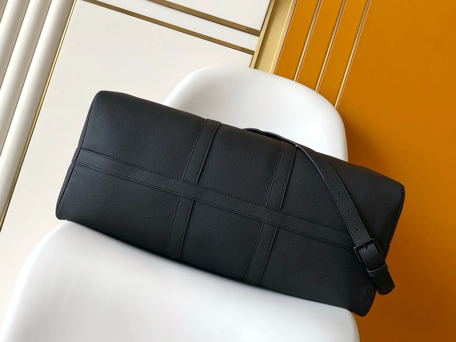 Louis Vuitton Keepall Bandouli&egrave;re 1:1 Aerogram black leather travel bag on a white chair - xiashuluxe
