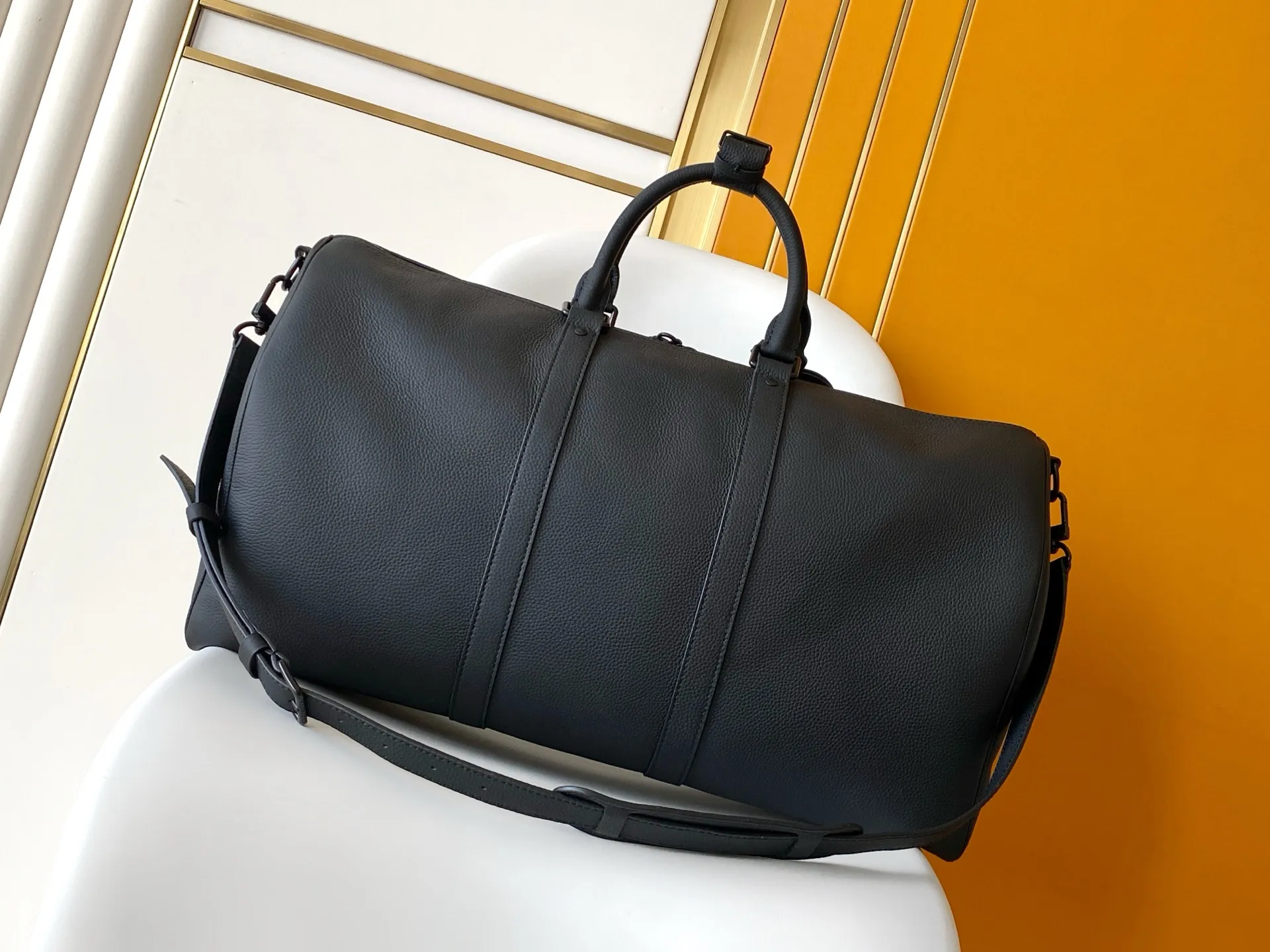 Louis Vuitton Keepall Bandoulière 1:1 Aerogram black leather travel bag on a white chair - xiashuluxe