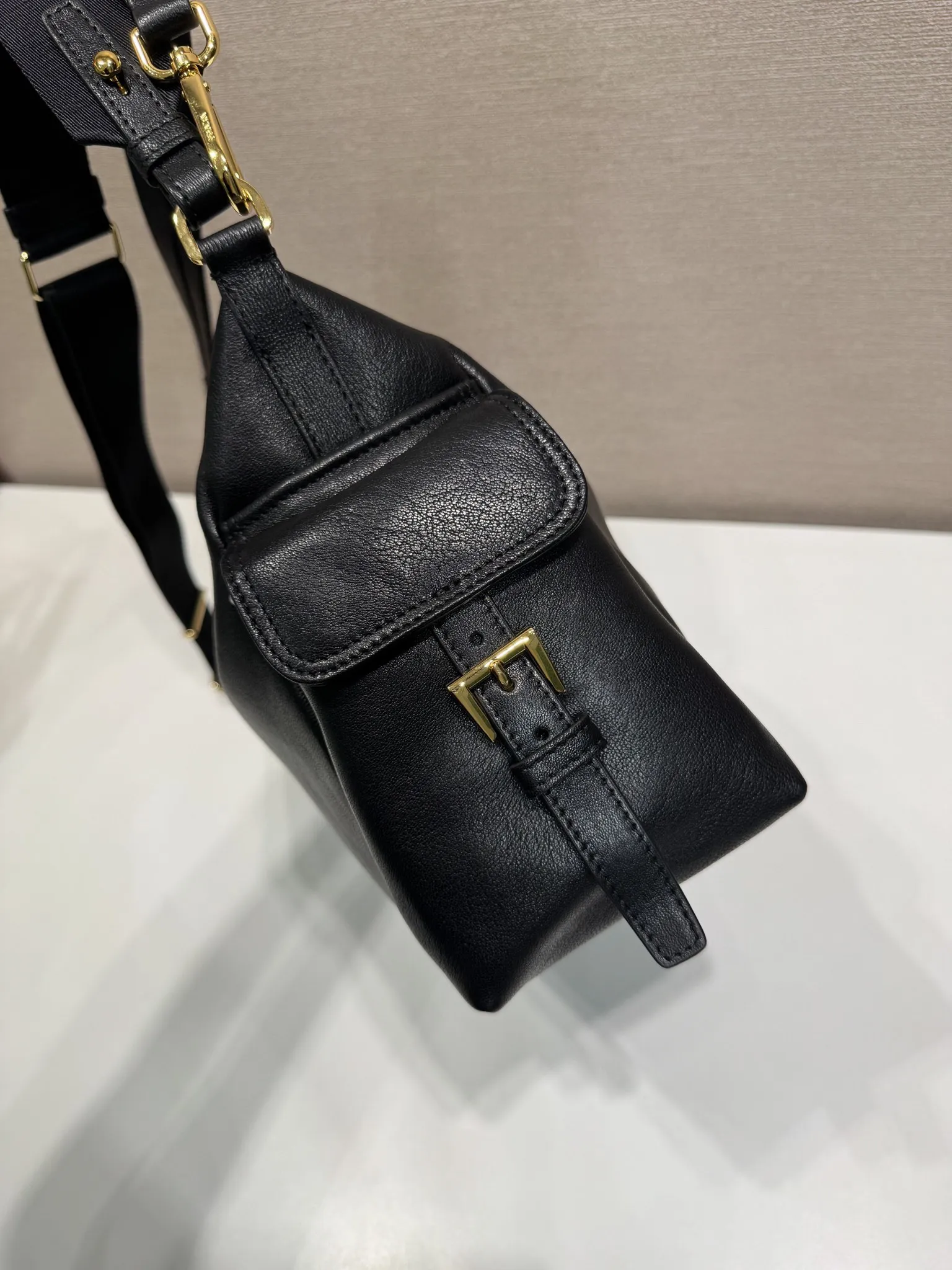 Prada 1:1 premium soft grained leather hobo bag in black with triangle logo and dual shoulder straps on display stand - xiashuluxe
