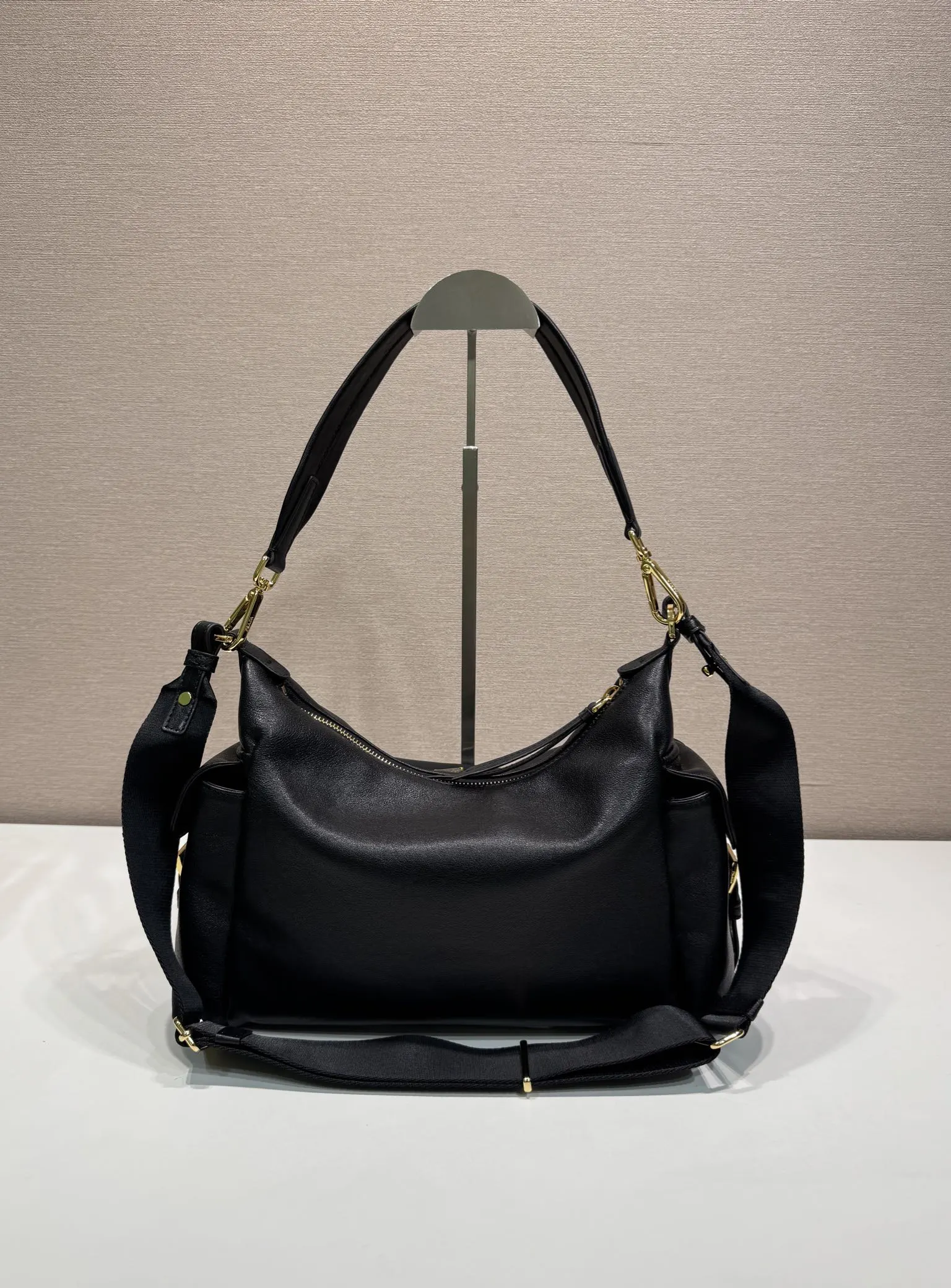 Prada 1:1 premium soft grained leather hobo bag in black with triangle logo and dual shoulder straps on display stand - xiashuluxe
