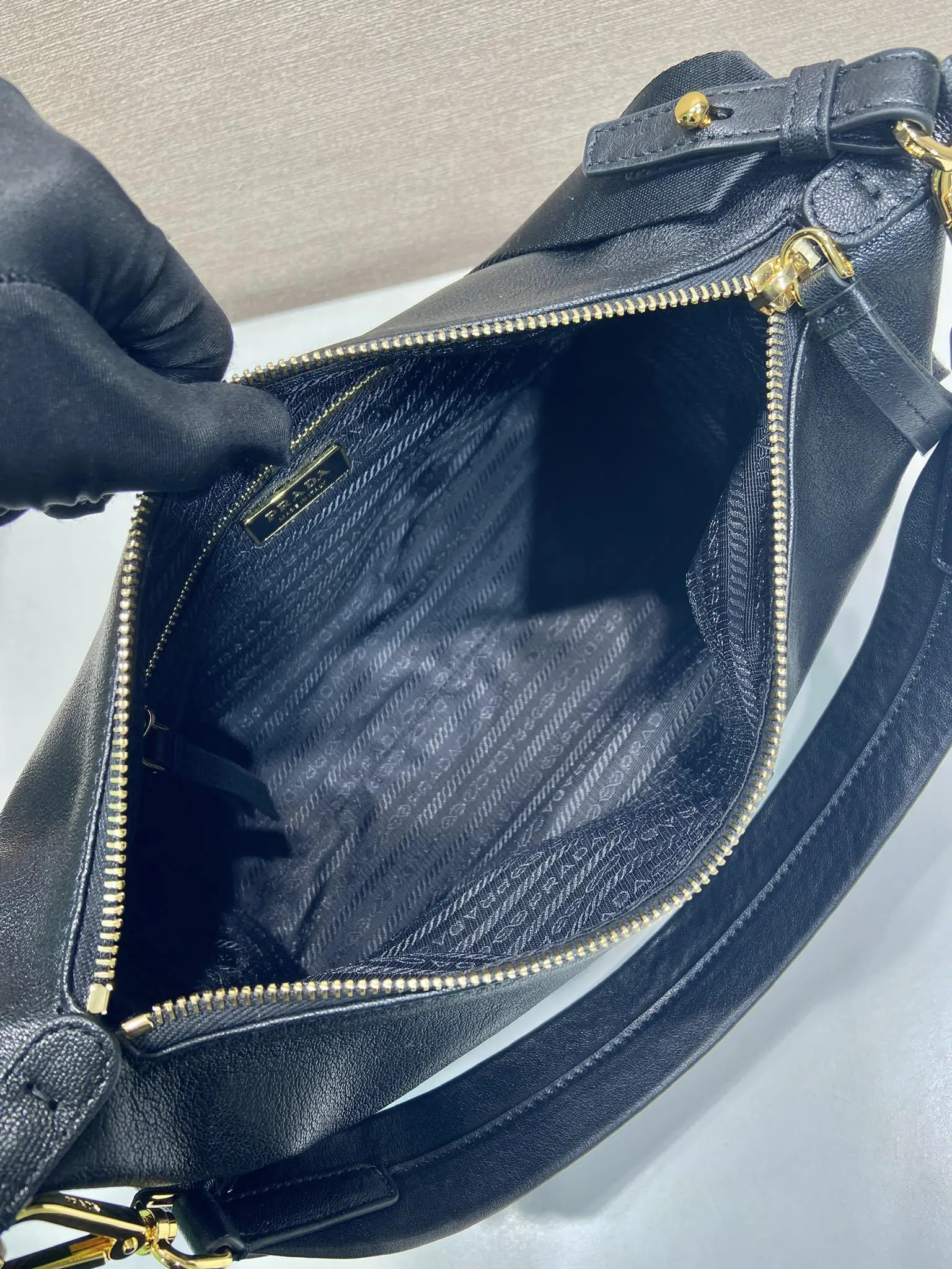 Prada 1:1 premium soft grained leather hobo bag in black with triangle logo and dual shoulder straps on display stand - xiashuluxe