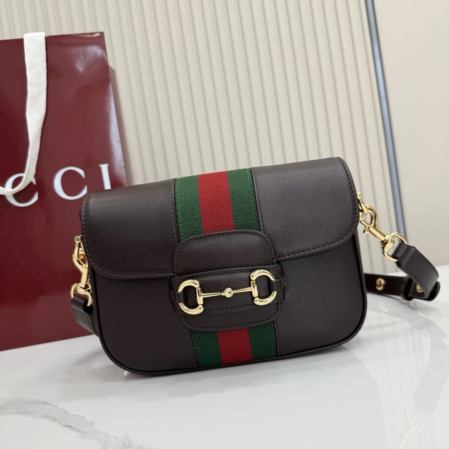 p660。【配全套专柜包装】‼️2026春夏系列全新上市。Gucci Horsebit 1955 系列包袋呈现柔韧雅致的廓形。此款式甄选柔软牛皮革打造,饰有Web织带细节,另配一条简约的可调节牛皮革肩带。 深棕色软皮 金色调配件 米色帆布衬里饰钻石菱格纹图案 马衔扣和织带 可拆卸和可调节牛皮革肩带,配搭扣,高:30厘米 翻盖开合 型号:866762。 尺寸:21厘米(宽)x 14.5厘米(高)x 5.5厘米(深) 重量:约0.5千克 颜色:深棕色/全皮。 意大利创作