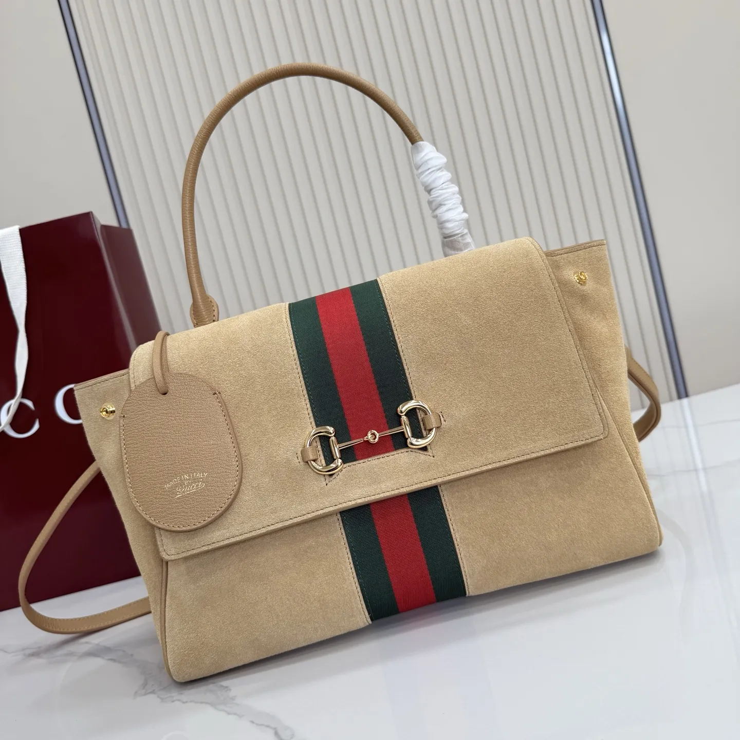 p710。【配全套包装】‼️Generation Gucci古驰世代系列深入探索品牌的典藏元素，将不同世代的设计融合为统一的美学叙事。这款款式以手提包设计向品牌标志性的马衔扣元素致敬，柔软的绒面皮革呈现精致的配色。 沙色柔软绒面材质 沙色皮革滚边 金色调配件 沙色帆布衬里，饰Diamante图案 马衔扣、织带和皮革标牌，带有&ldquo;Made in Italy Gucci&rdquo;标志 饰按扣 内部：1个拉链口袋，1个开口口袋 手柄垂直高度：17厘米 可拆卸和可调节皮革肩带下垂长度：42 - 54厘米；长度：93 - 112厘米 磁扣开合 型号：875018。 尺寸：30厘米（宽）x 21厘米（高）x 12厘米（深） 重量：约685克 颜色：杏色/绒皮。 意大利创作