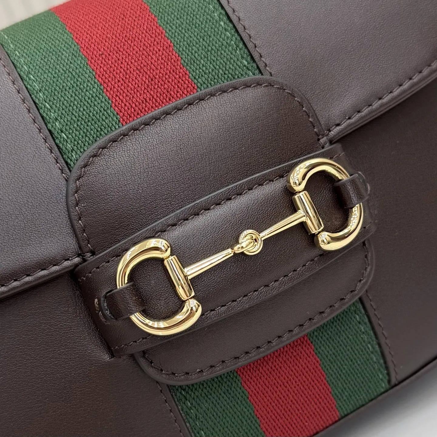 p660。【配全套专柜包装】‼️2026春夏系列全新上市。Gucci Horsebit 1955 系列包袋呈现柔韧雅致的廓形。此款式甄选柔软牛皮革打造，饰有Web织带细节，另配一条简约的可调节牛皮革肩带。 深棕色软皮 金色调配件 米色帆布衬里饰钻石菱格纹图案 马衔扣和织带 可拆卸和可调节牛皮革肩带，配搭扣，高：30厘米 翻盖开合 型号：866762。 尺寸：21厘米（宽）x 14.5厘米（高）x 5.5厘米（深） 重量：约0.5千克 颜色：深棕色/全皮。 意大利创作