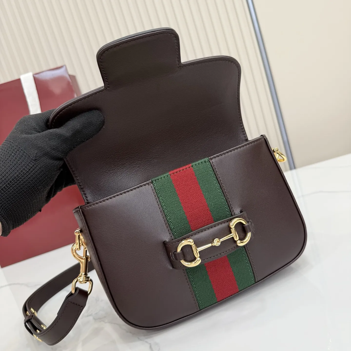 p660。【配全套专柜包装】‼️2026春夏系列全新上市。Gucci Horsebit 1955 系列包袋呈现柔韧雅致的廓形。此款式甄选柔软牛皮革打造，饰有Web织带细节，另配一条简约的可调节牛皮革肩带。 深棕色软皮 金色调配件 米色帆布衬里饰钻石菱格纹图案 马衔扣和织带 可拆卸和可调节牛皮革肩带，配搭扣，高：30厘米 翻盖开合 型号：866762。 尺寸：21厘米（宽）x 14.5厘米（高）x 5.5厘米（深） 重量：约0.5千克 颜色：深棕色/全皮。 意大利创作