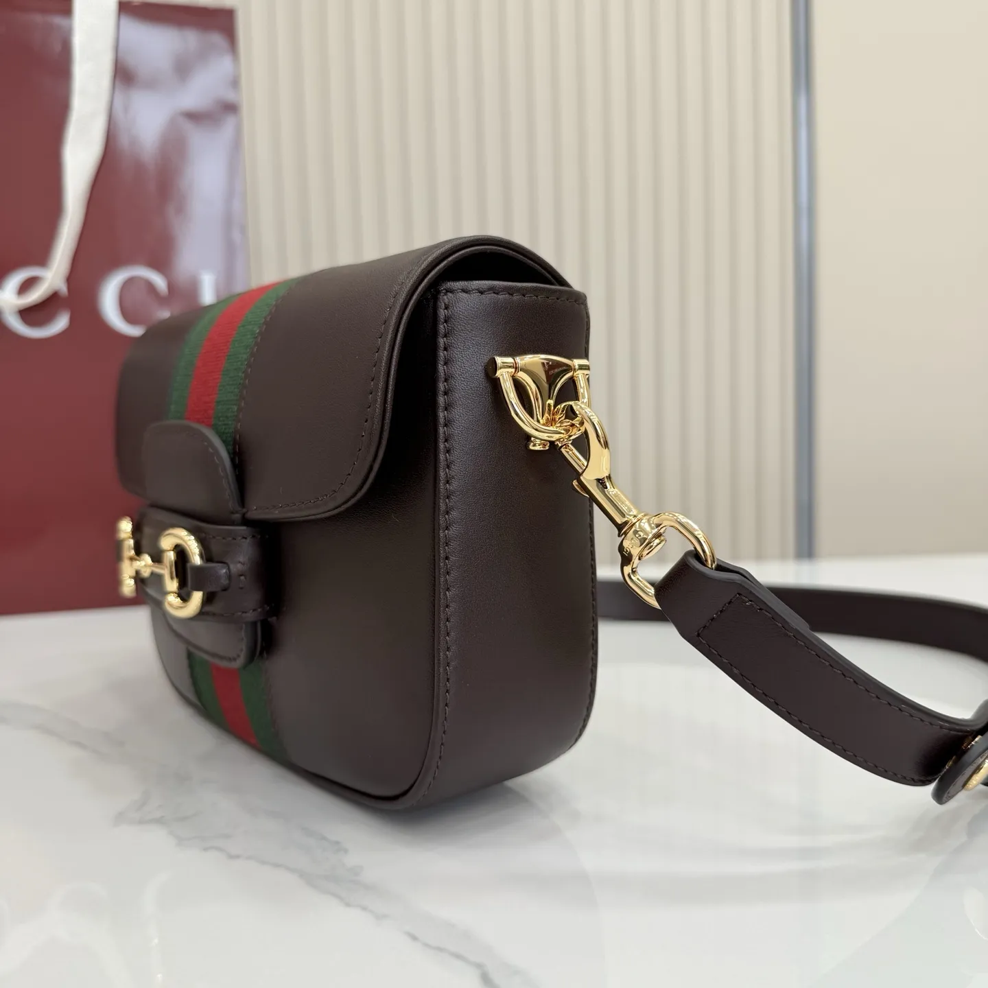 p660。【配全套专柜包装】‼️2026春夏系列全新上市。Gucci Horsebit 1955 系列包袋呈现柔韧雅致的廓形。此款式甄选柔软牛皮革打造,饰有Web织带细节,另配一条简约的可调节牛皮革肩带。 深棕色软皮 金色调配件 米色帆布衬里饰钻石菱格纹图案 马衔扣和织带 可拆卸和可调节牛皮革肩带,配搭扣,高:30厘米 翻盖开合 型号:866762。 尺寸:21厘米(宽)x 14.5厘米(高)x 5.5厘米(深) 重量:约0.5千克 颜色:深棕色/全皮。 意大利创作