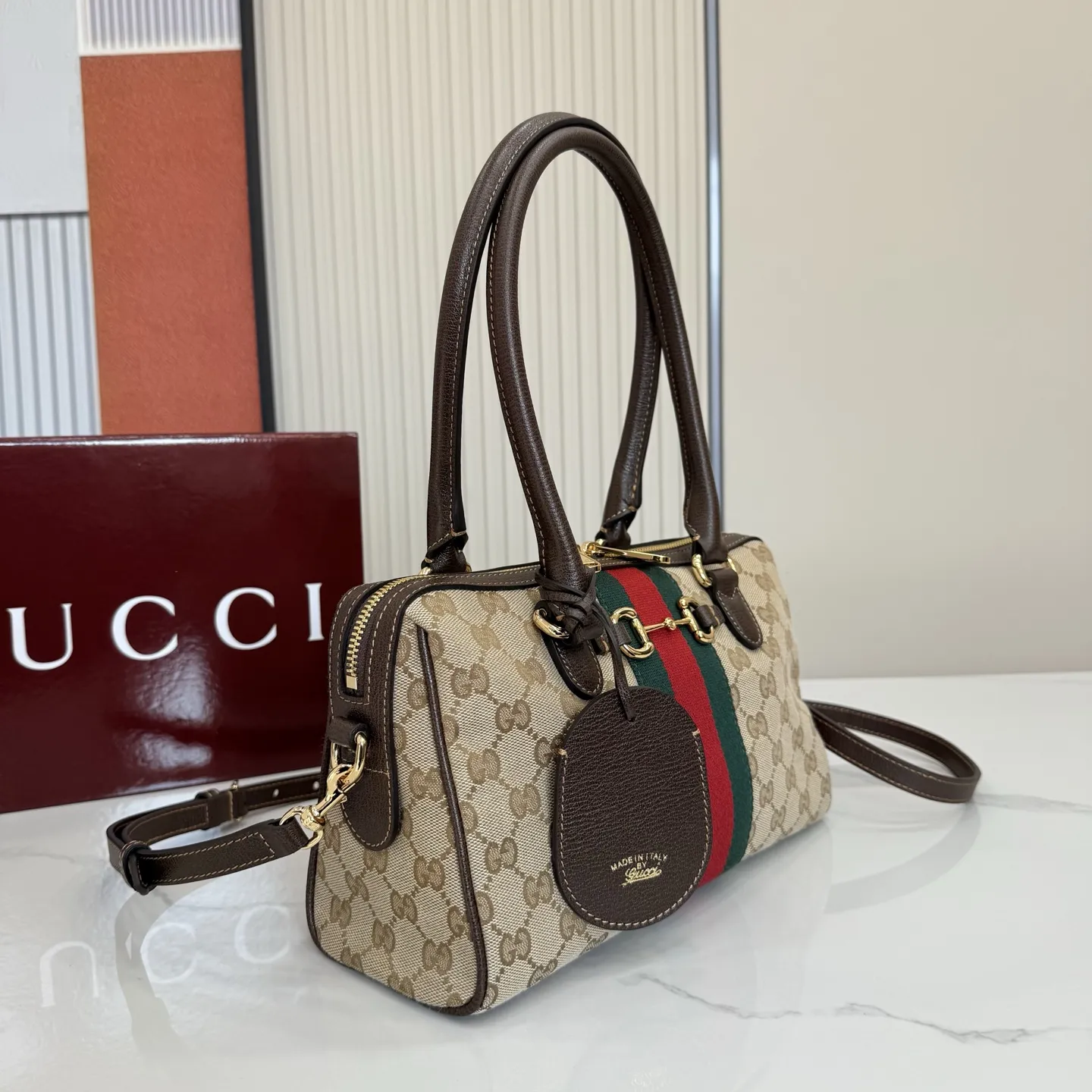 p640。【配全套专柜包装】‼️2026春夏系列全新上市。Gucci Borsetto系列名称巧妙融合意大利语“borsa”(手袋)和“morsetto”(马衔扣)二词。 这款手袋甄选轻盈挺括的GG帆布打造,以复古风格沙色配色匠心呈献,源自典藏的钻石菱格纹图案演绎全新衬里。 沙色和深棕色GG帆布 深棕色软皮皮革滚边 金色调配件 米色帆布衬里饰钻石菱格纹图案 Horsebit、Web和皮革标签,带有“Made in Italy by Gucci”标志 手柄高:20cm 可拆卸和可调节的皮革肩带,高:44 - 50厘米;长度:100 - 115厘米 双拉链开合 型号:866732。 尺寸:28厘米(宽)x 15厘米(高)x 10厘米(深) 重量:约0.5千克 颜色:杏布/棕色。 意大利创作