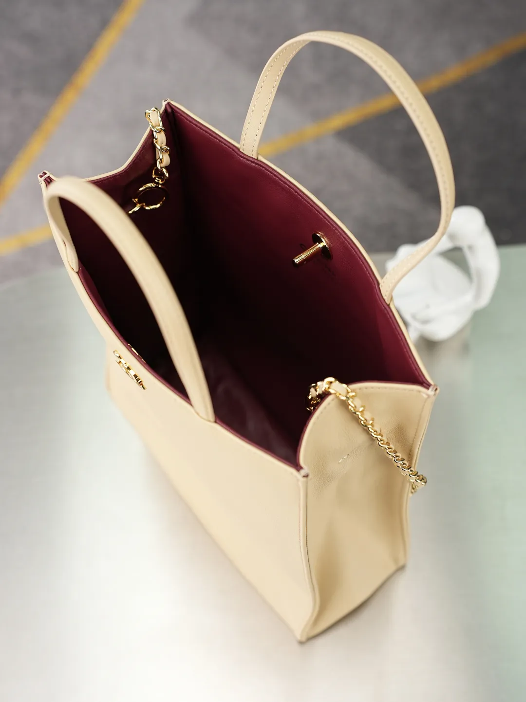 💼𝑪𝒉𝒂𝒏𝒆𝒍 𝟐𝟔𝑨 | 新款🆕高级手工坊👜 「图片小号」💜独家背景💜实物实拍/顶级质量 ✨奶茶光面小牛皮竖款托特包🤎，细腻平滑头层牛皮搭配利落方正包型🌼，亮金色旋扣标识精致醒目，搭配同皮短提手与可调节穿皮金属长链，手提斜挎两种背法随心切换，内里酒红色真皮内衬质感出众，磁吸按扣开合便捷，包身走线工整立体不易变形，底部平整支撑版型挺括，五金刻印清晰细腻，柔和浅奶茶色调自带温婉通勤氛围感☀️，日常通勤、逛街出行都十分适配。 款号：6452 颜色如图所示💝带包装盒 尺寸：𝟐𝟖.𝟓&times;𝟐𝟑.𝟓&times;𝟗.𝟓𝒄𝒎