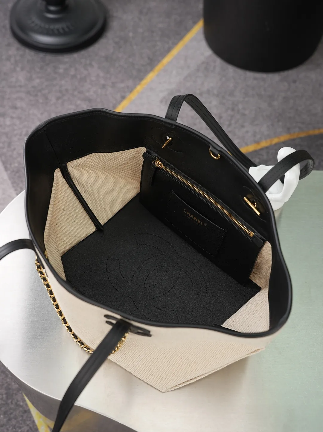 💼𝑪𝒉𝒂𝒏𝒆𝒍 𝟐𝟔𝑺 | 帆布托特沙滩包👜 💜独家背景💜实物实拍/顶级质量 ✨米白帆布拼黑色牛皮托特包🤍，肌理紧实耐磨的米调帆布搭配细腻光面牛皮包边🌼，两侧立体双C皮标搭配穿皮复古金链条，简约撞色层次柔和，加宽同皮长肩带减负舒适，单肩背负随性松弛，包身可折叠三角底设计灵活扩容，内里全黑真皮衬里搭配烫金标识，内设拉链隔袋与卡位小包，五金刻印清晰规整，清爽浅帆布弱化厚重感，春夏通勤出行适配度拉满☀️，轻松打造简约轻奢休闲造型。 款号：6282 颜色如图所示 尺寸：𝟐𝟎&times;𝟒𝟑&times;𝟏𝟕𝒄𝒎