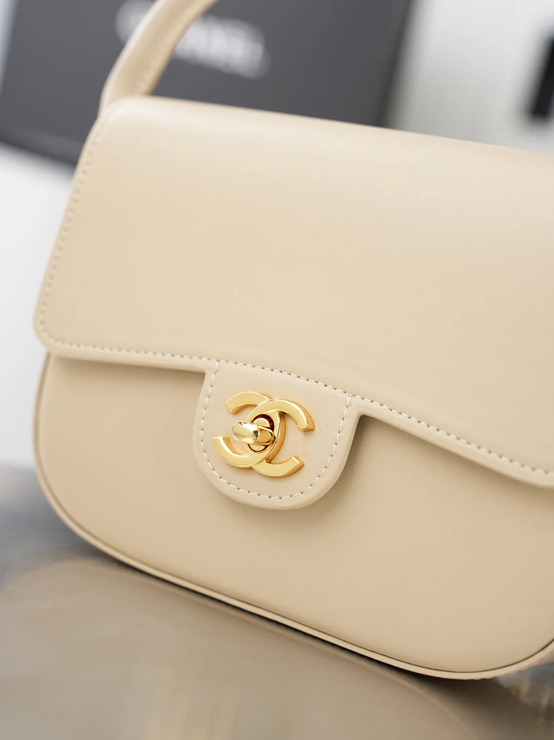 💼𝑪𝒉𝒂𝒏𝒆𝒍 𝟐𝟔𝑨 | 新品🆕手柄口盖包👜 💜独家背景💜实物实拍/顶级质量 ✨浅米色平滑光面小牛皮手提马鞍包🤍,细腻软糯的平纹牛皮搭配利落圆弧包身🌼,亮金色旋扣标识精致醒目,自带一体式同皮短提手,搭配可穿皮调节金属细链条,手提、斜挎两种背法随心切换,侧边皮扣细节做工工整,内里酒红色真皮衬里搭配金属刻印铭牌,走线细密均匀,柔和浅米色自带温婉日常氛围感☀️通勤约会各种穿搭都能轻松适配。 款号:6424 杏色牛皮 尺寸:𝟏𝟒.𝟓×𝟏𝟗.𝟓×𝟓𝒄𝒎