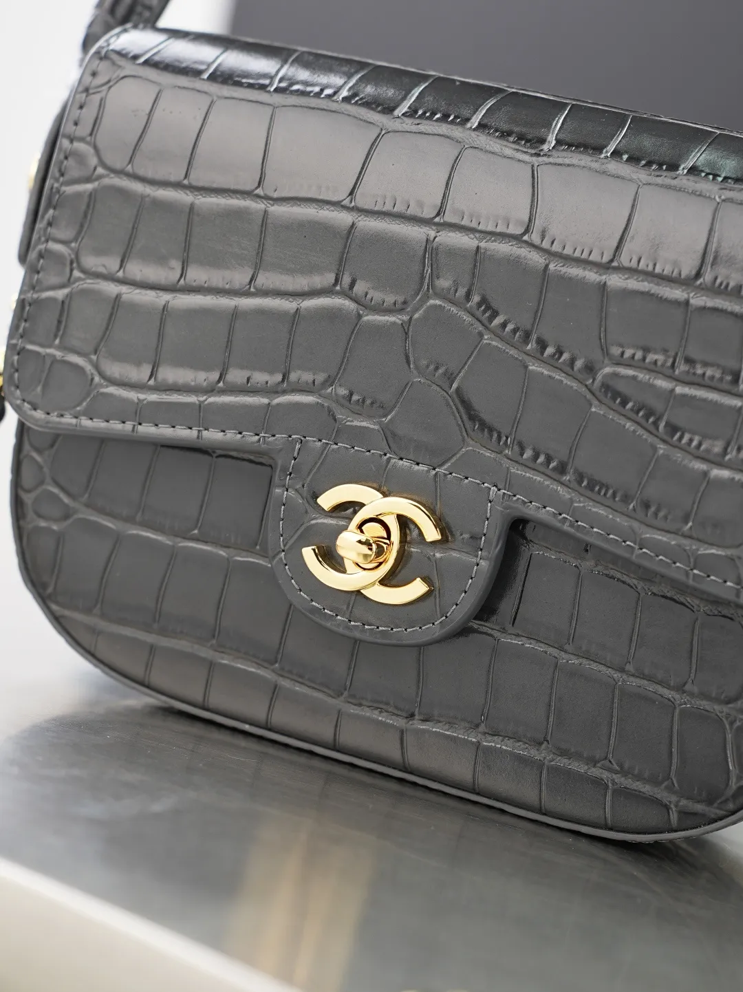 💼𝑪𝒉𝒂𝒏𝒆𝒍 𝟐𝟔𝑨 | 新品🆕手柄口盖包👜 💜独家背景💜实物实拍/顶级质量 ✨深灰色亮面漆皮菱格链条包🖤,细腻亮泽漆皮搭配工整菱格绗缝🌼,冷调银质锁扣简约高级,可调节穿皮金属链条随心调整长度,单肩斜挎都合适,包身轮廓立体有型,内衬细腻耐磨,五金纹路做工精细,低调灰调自带清冷高级感☀️,通勤日常搭配各类服饰都很出彩。 款号:6424 深灰色鳄鱼纹 尺寸:𝟏𝟒.𝟓×𝟏𝟗.𝟓×𝟓𝒄𝒎