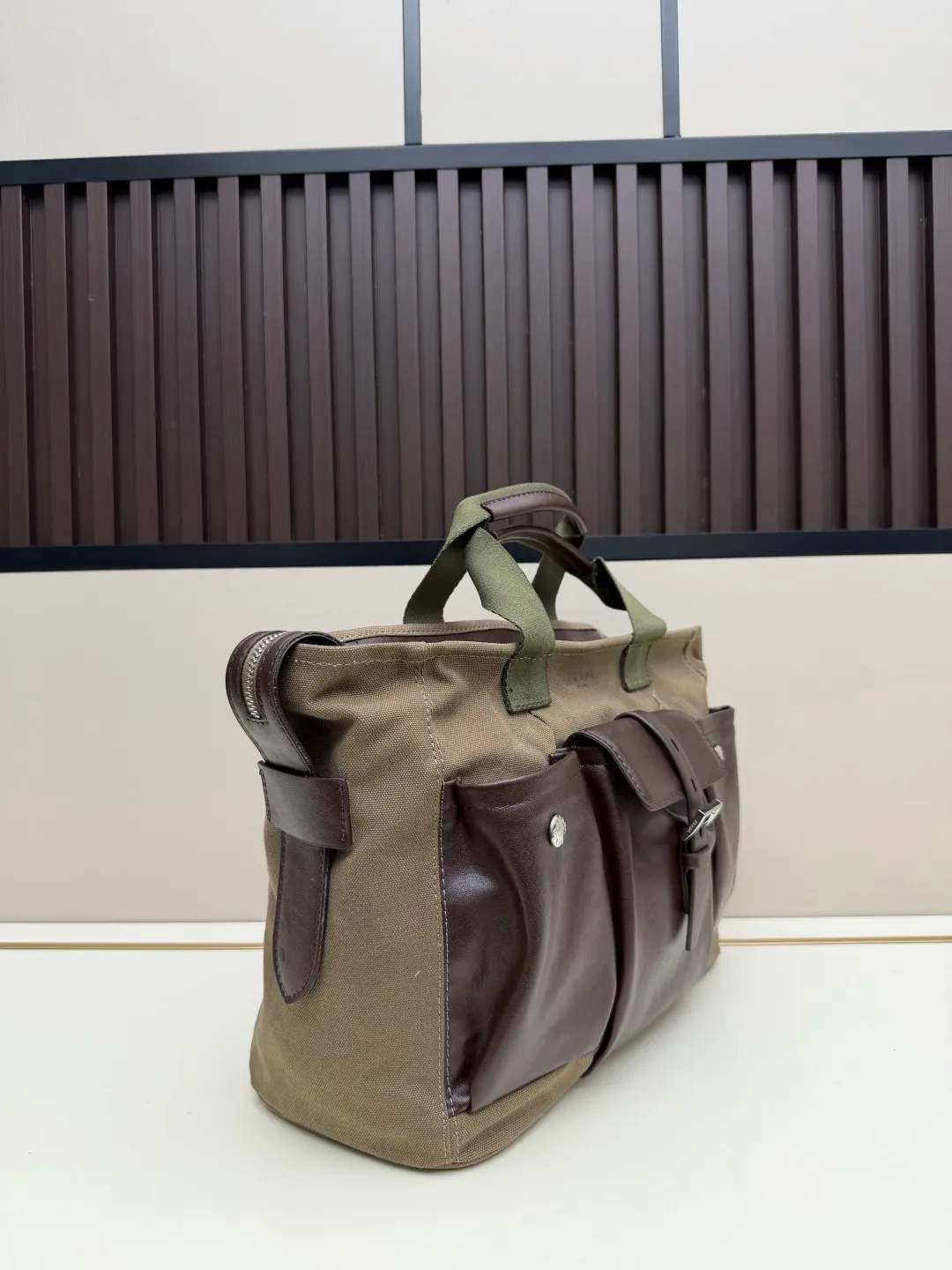 批 210💰👜Prada 春夏Route系列多口袋帆布包，军旅风设计超有型！卡其帆布+棕色皮革拼接，质感满分✨。正面多口袋，按扣&搭扣超实用，收纳力强，通勤or短途旅行都很适合。配可调节肩带，手提斜挎都OK，男女都能轻松驾驭，时尚又百搭！ 尺寸35-24-15，型号2633