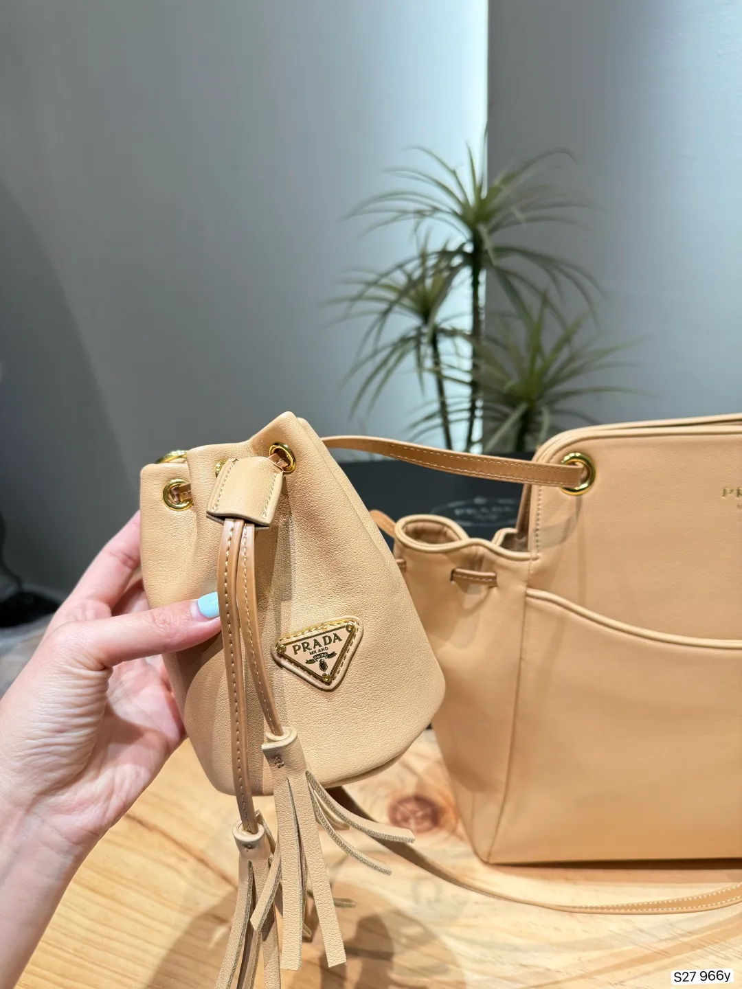 P185 配盒子 普拉达Prada水桶包​​ 👜Prada手感柔软又耐用，金属配件超有质感✨。简约大方的设计，奶昔色温柔百搭，通勤或休闲都能轻松驾驭。肩带可调节，手提斜挎都OK，内部空间合理，日常物品轻松收纳。水桶包造型经典，实用又时髦，是Prada热门单品之一！ 尺寸28 23 货号966