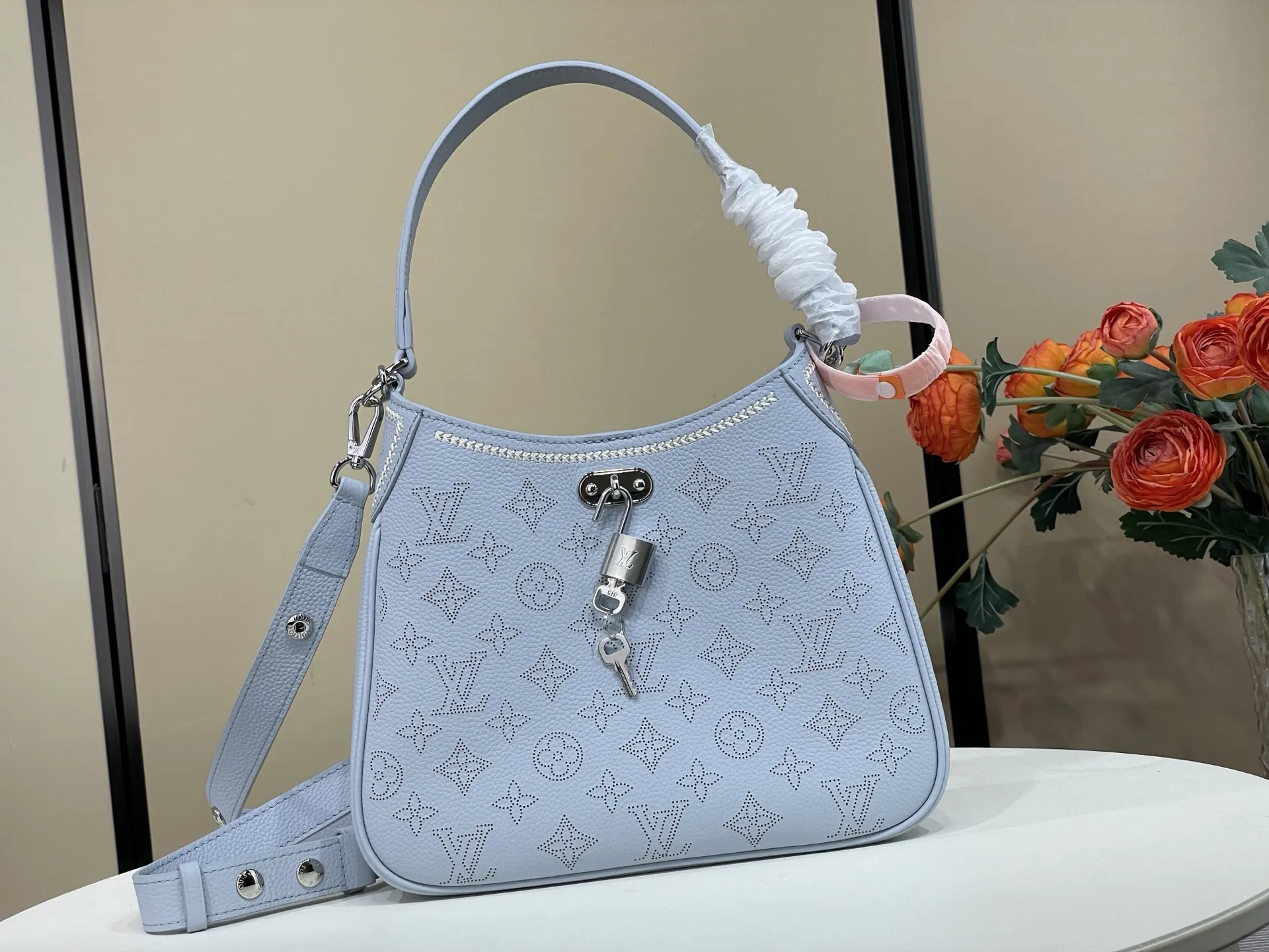 复刻独家实拍📷【ALL AROUND 小号手袋 】 m28779 蓝色（冲孔） Mahina Couture 系列以优雅色调重绎 All Around 小号手袋，再为牛皮革铺陈Monogram 穿孔图案，与编织纹理刺绣细节共筑色彩反差。标志性 LV 挂锁点睛考究构型，可调节肩带提供多种背携方式。 尺寸：25 x 20 x 6 厘米 (长度 x 高 x 宽)
