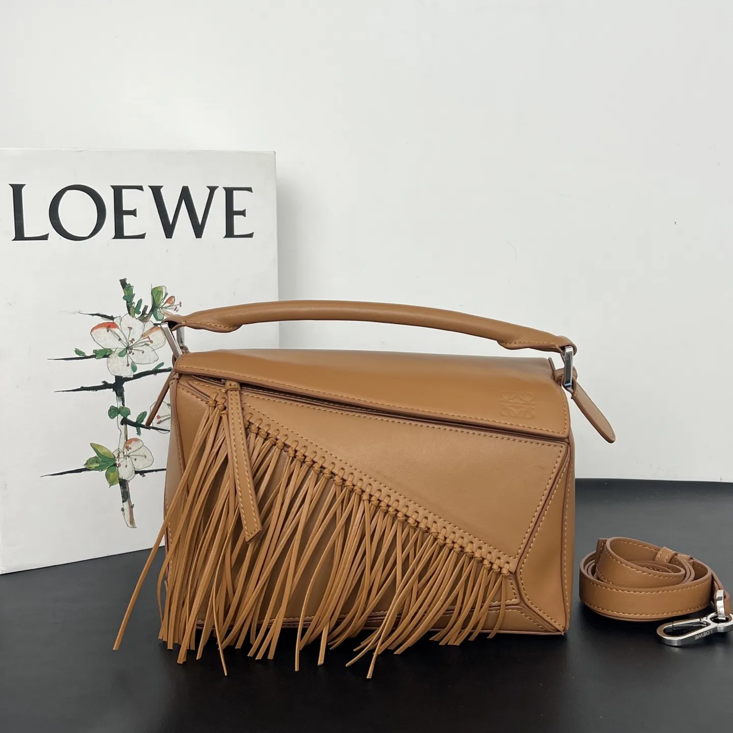 💰310 Loewe puzzle 新品 头层牛皮 流苏几何包 几何包型上的飘逸&ldquo;马鬃&rdquo; 今年的Puzzle，最妙的是包身上同色调的流苏装饰，就像骏马奔跑时飞扬的鬃毛，瞬间打破了Puzzle标志性几何拼接的冷静感，多了一份灵动和潇洒。黑白双色取自骏马灵感，更添一分别样的松弛和洒脱。尺寸 24&times;10.5&times;16.5cm 款号：193