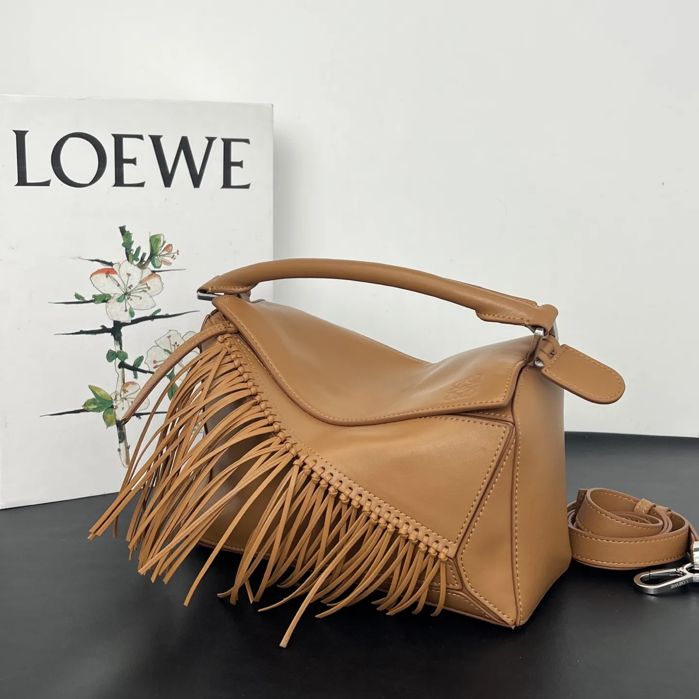 💰310 Loewe puzzle 新品 头层牛皮 流苏几何包 几何包型上的飘逸&ldquo;马鬃&rdquo; 今年的Puzzle，最妙的是包身上同色调的流苏装饰，就像骏马奔跑时飞扬的鬃毛，瞬间打破了Puzzle标志性几何拼接的冷静感，多了一份灵动和潇洒。黑白双色取自骏马灵感，更添一分别样的松弛和洒脱。尺寸 24&times;10.5&times;16.5cm 款号：193