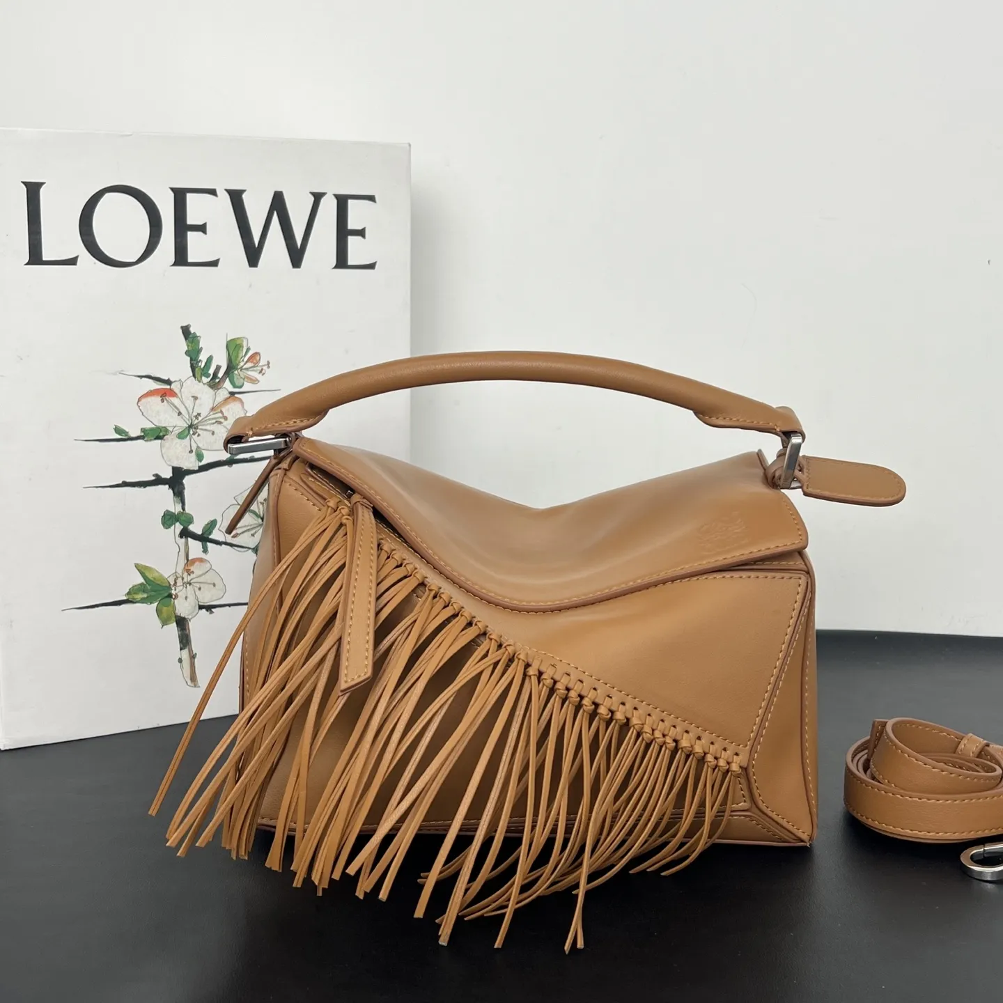 💰310 Loewe puzzle 新品 头层牛皮 流苏几何包 几何包型上的飘逸“马鬃” 今年的Puzzle,最妙的是包身上同色调的流苏装饰,就像骏马奔跑时飞扬的鬃毛,瞬间打破了Puzzle标志性几何拼接的冷静感,多了一份灵动和潇洒。黑白双色取自骏马灵感,更添一分别样的松弛和洒脱。尺寸 24×10.5×16.5cm 款号:193