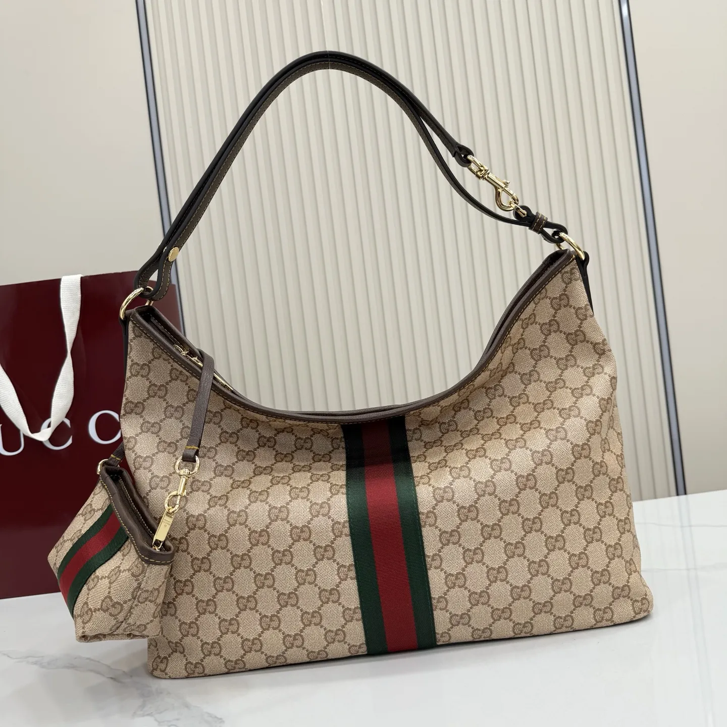 p580。【配全套包装】‼️Generation Gucci古驰世代系列深入探索品牌的典藏元素，将不同世代的设计融合为统一的美学叙事。全新单肩包，兼具多功能与精致感，可斜挎或肩背。可拆卸迷你包可收纳AirPods及小件物品，增添实用而灵动的细节。 沙色和深棕色GG涂层帆布 棕色皮革滚边 金色调配件 织带 GG涂层帆布和棕色棉布衬里 双拉链开合 型号：A008NS。 尺寸：39.5厘米（宽）x 29厘米（高）x 15.5厘米（深） 滑动肩链带高：31厘米 - 54厘米 颜色：杏色/水晶。 意大利创作