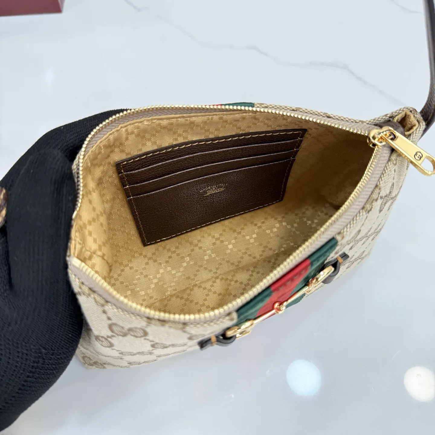 p420。【配全套包装】‼️Generation Gucci古驰世代系列深入探索品牌的典藏元素，将不同世代的设计融合为统一的美学叙事。小皮具设计向马衔扣致敬，将标志性配件细节与Web条纹织带融合，注入复古优雅气息。这款款式采用GG帆布制作，并配有可调节肩带。 沙色和深棕色GG帆布 棕色皮革滚边 金色调配件 沙色帆布衬里，饰有钻石菱格纹图案和棕色塔夫绸衬里 马衔扣、织带和意大利创作Gucci标识 内部：3个卡片隔层 可调节皮革肩带，下垂长度：30厘米 拉链封口 型号：867130。 尺寸：20厘米（宽）x 12.5厘米（高）x 4.5厘米（下深）x 1.5厘米（上深） 重量：约 166 克 颜色：杏布/棕色。 意大利创作