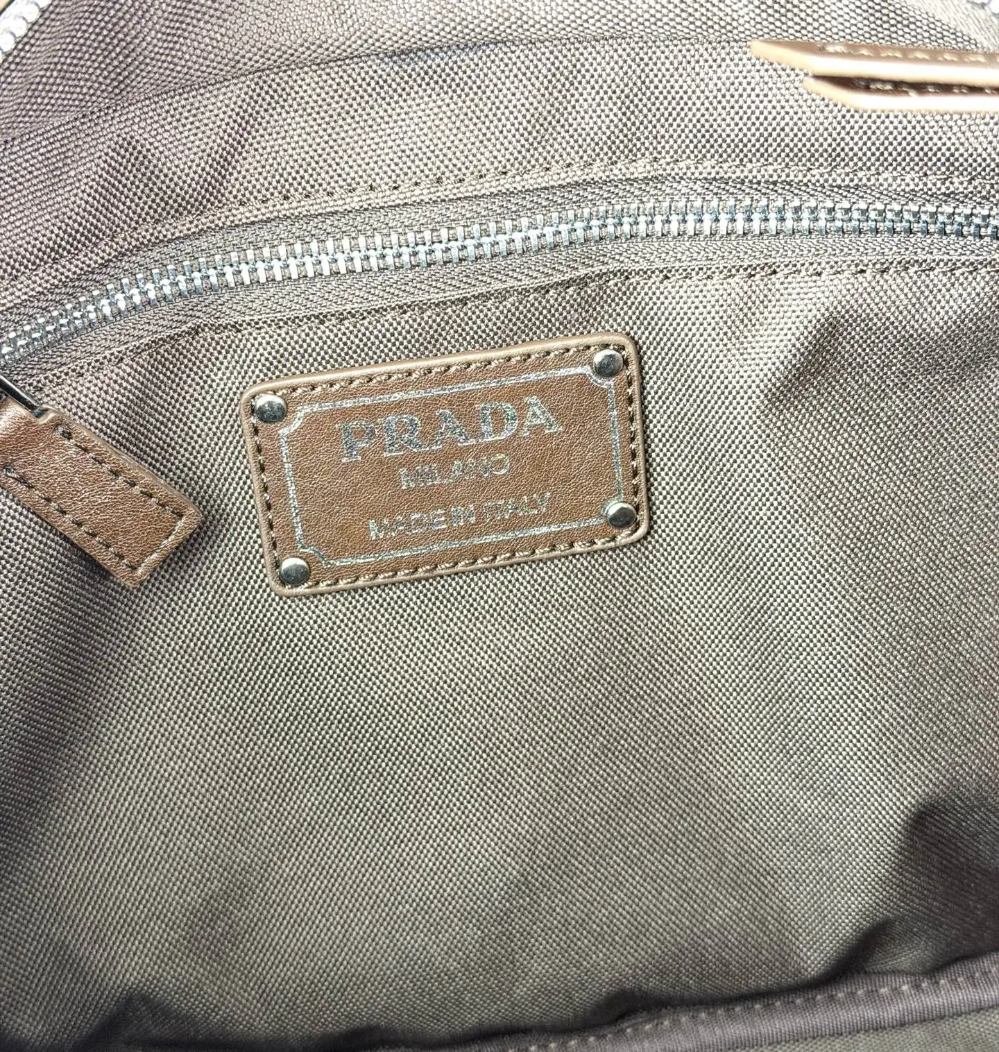 💰280 💥🔥 Prada Route系列托特包 👜采用柔韧耐造的纹理皮革,包身利落的梯形结构,正面设有带扣翻盖口袋,搭配顶部双提手,整体线条硬朗,自带复古机车感。 ‼️标志性肩带:配备印有 “PRADA” 字母的宽版织带,可斜挎也可单肩,是Route系列最显著的识别符号,视觉冲击力强 款号:660 尺寸:28×21×13cm