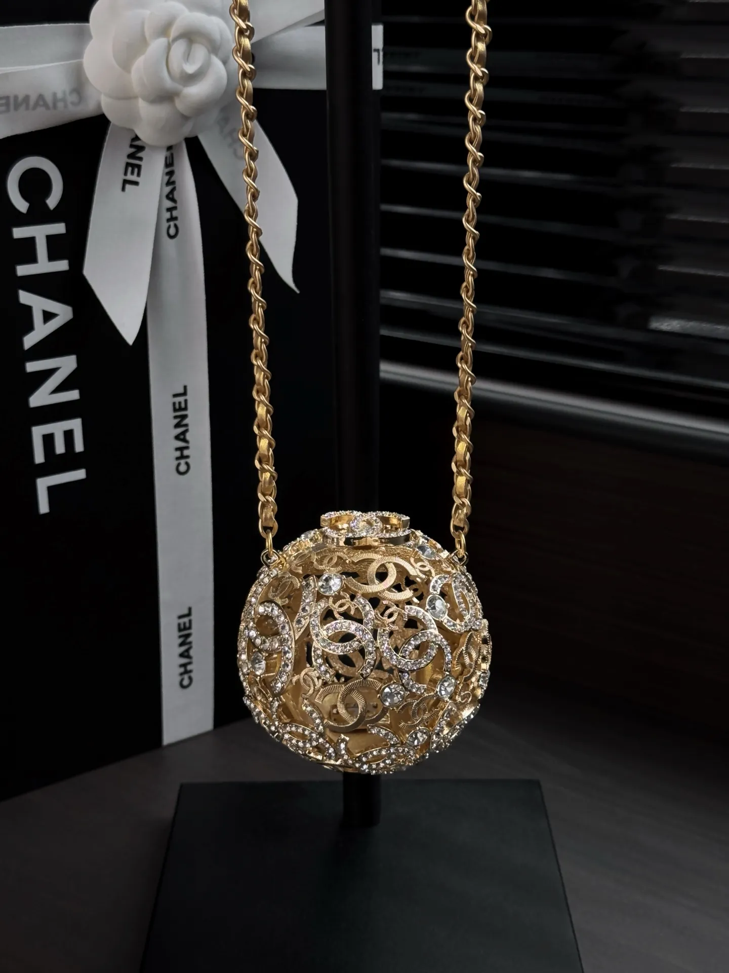 Chanel 25A 手工坊系列金色镂空球形晚宴包。 整只包是一颗金属球体, 巴洛克 风格的镂空花纹 + 漫天水钻镶嵌,中间嵌着双C Logo,链条肩带也是金色粗链设计,整体非常华丽复古。属于 Chanel 手工坊的收藏家级作品。 这种球形镂空金属工艺灵感来自传统香囊/挂坠的设计,搭配满钻之后更像一件可佩戴的艺术品。基本上是为了晚宴、红毯、派对这类重要场合而生,日常实用性几乎为零,但辨识度拉满。