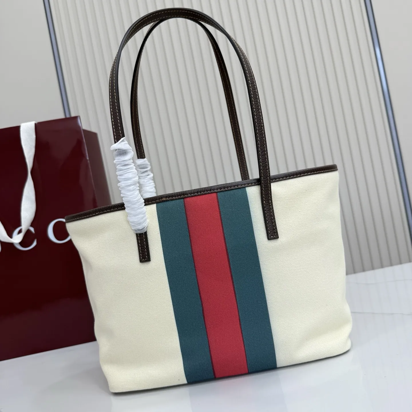 p480。【配全套包装】‼️Generation Gucci系列深入探索品牌典藏元素，将不同世代的设计融入一体，营造出独特的美学叙事。水洗GG帆布为精致廓形增添品牌标识性细节，如这款托特包，通过魅力装饰和品牌标识徽牌，将日常风格提升至新高度。 天然水洗帆布 棕色皮革滚边 金色调配件 棕色皮革吊饰 米色和深棕色棉质衬里 提手下垂：23厘米 饰按扣闭合 型号：A0034E。 尺寸：25厘米（宽）x 19厘米（高）x 11.5厘米（深） 重量：约260克 颜色：棕色/帆布。 意大利创作