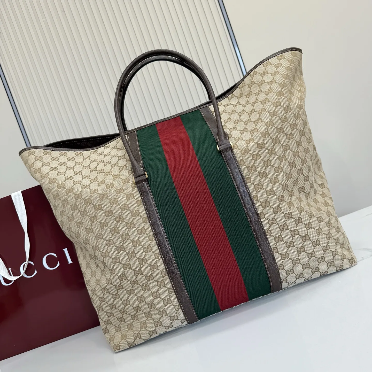 p630。‼️Generation Gucci系列深入探索品牌典藏元素，将不同年代的设计融合成一种美学叙事。GG涂层帆布搭配织带，为精致廓形增添品牌标识性元素，例如这款旅行包，提升日常使用体验。 沙色和深棕色GG涂层帆布 棕色皮革滚边 金色调配件 织带 棕色棉布衬里 型号：874979。 尺寸：47厘米（宽）x45厘米（高）x19.8厘米（侧宽）。 颜色：杏布/棕色。