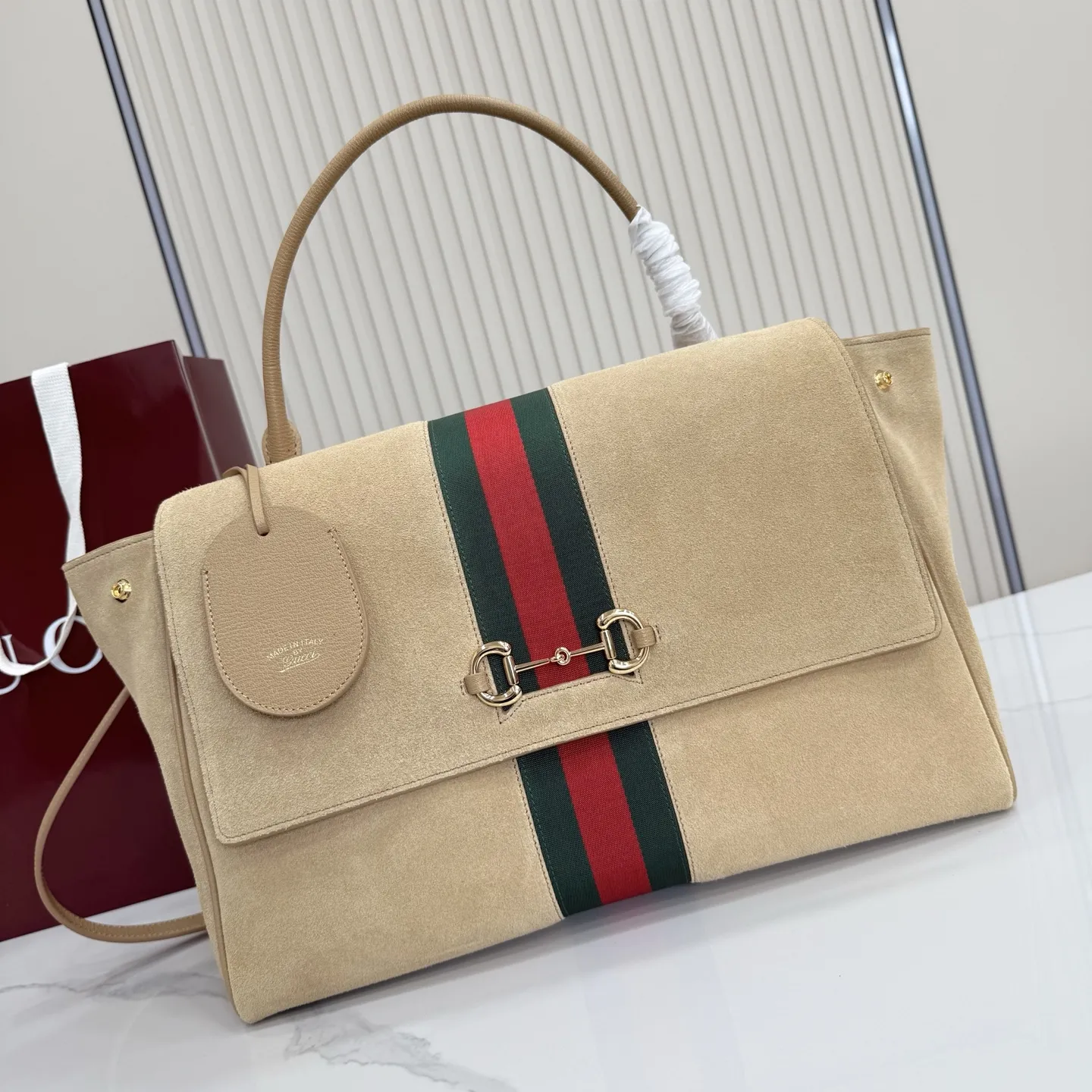 p790。【配全套包装】‼️Generation Gucci古驰世代系列深入探索品牌的典藏元素，将不同世代的设计融合为统一的美学叙事。这款款式以手提包设计向品牌标志性的马衔扣元素致敬，柔软的绒面皮革呈现精致的配色。 沙色柔软绒面材质 沙色皮革滚边 金色调配件 沙色帆布衬里，饰Diamante图案 马衔扣、织带和皮革标牌，带有&ldquo;Made in Italy Gucci&rdquo;标志 饰按扣 内部：1个拉链口袋，1个开口口袋 手柄垂直高度：18-24.5厘米 可拆卸和可调节皮革肩带下垂长度：51 - 55厘米； 磁扣开合 型号：875019。 尺寸：37厘米（宽）x 29厘米（高）x 13厘米（深） 重量：约825克 颜色：杏色/绒皮。 意大利创作