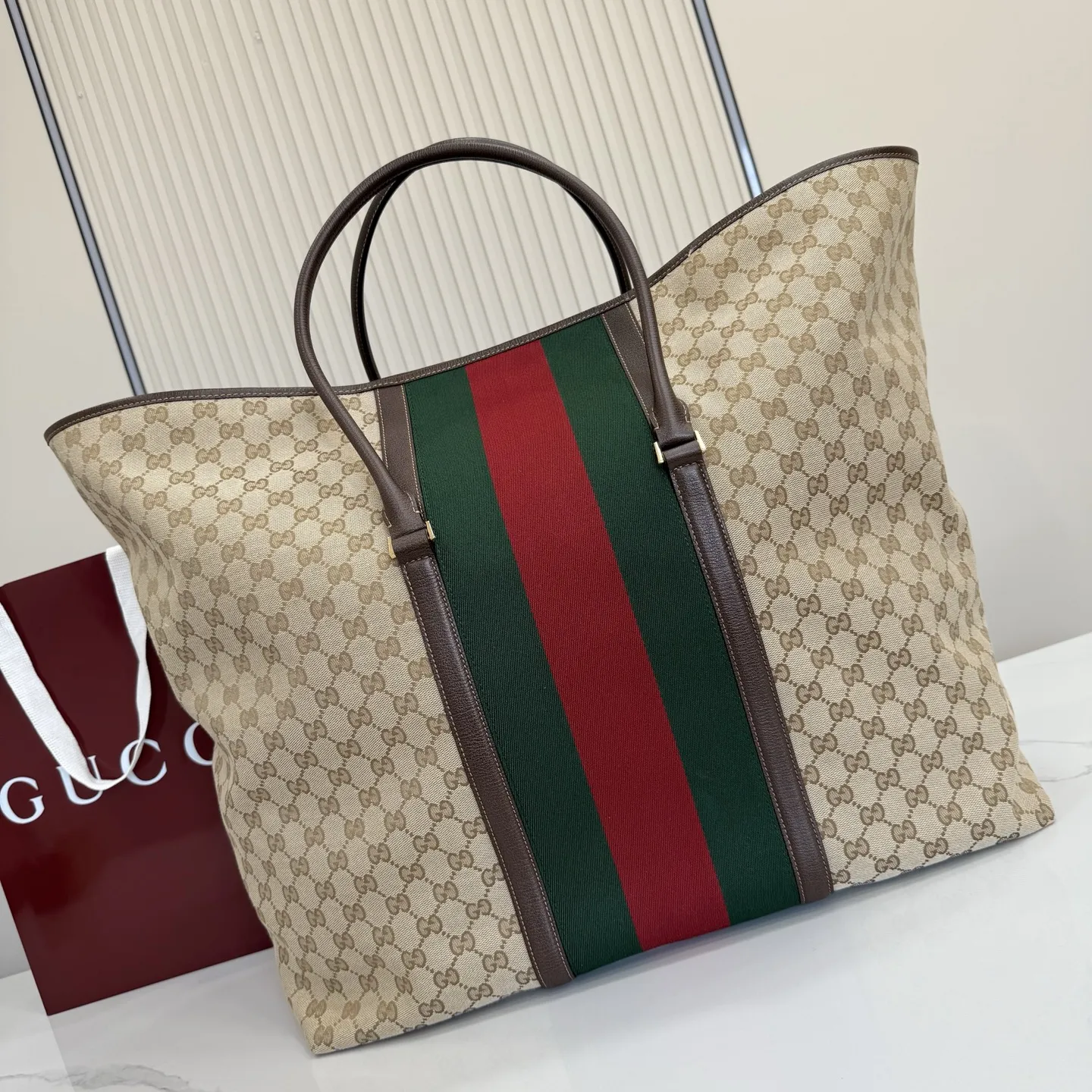 p630。‼️Generation Gucci系列深入探索品牌典藏元素，将不同年代的设计融合成一种美学叙事。GG涂层帆布搭配织带，为精致廓形增添品牌标识性元素，例如这款旅行包，提升日常使用体验。 沙色和深棕色GG涂层帆布 棕色皮革滚边 金色调配件 织带 棕色棉布衬里 型号：874979。 尺寸：47厘米（宽）x45厘米（高）x19.8厘米（侧宽）。 颜色：杏布/棕色。