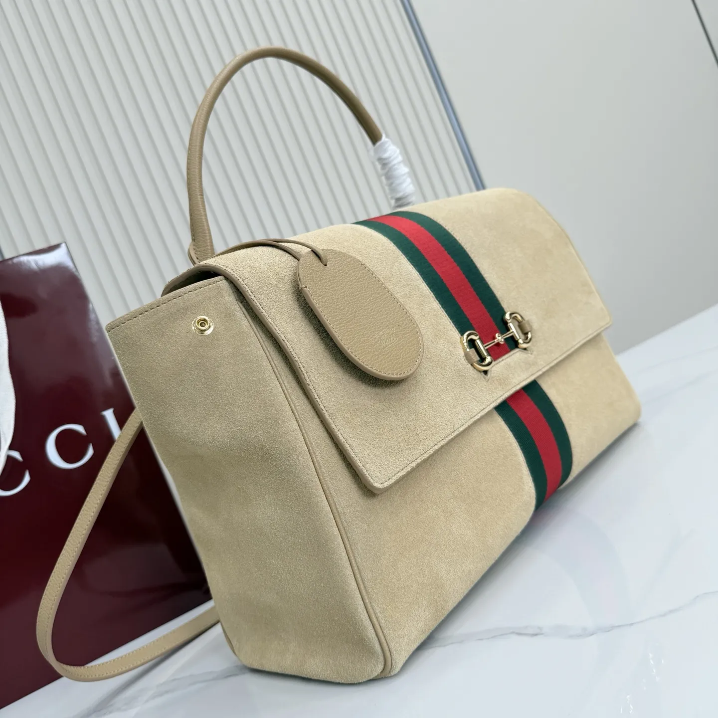 p790。【配全套包装】‼️Generation Gucci古驰世代系列深入探索品牌的典藏元素,将不同世代的设计融合为统一的美学叙事。这款款式以手提包设计向品牌标志性的马衔扣元素致敬,柔软的绒面皮革呈现精致的配色。 沙色柔软绒面材质 沙色皮革滚边 金色调配件 沙色帆布衬里,饰Diamante图案 马衔扣、织带和皮革标牌,带有“Made in Italy Gucci”标志 饰按扣 内部:1个拉链口袋,1个开口口袋 手柄垂直高度:18-24.5厘米 可拆卸和可调节皮革肩带下垂长度:51 - 55厘米; 磁扣开合 型号:875019。 尺寸:37厘米(宽)x 29厘米(高)x 13厘米(深) 重量:约825克 颜色:杏色/绒皮。 意大利创作