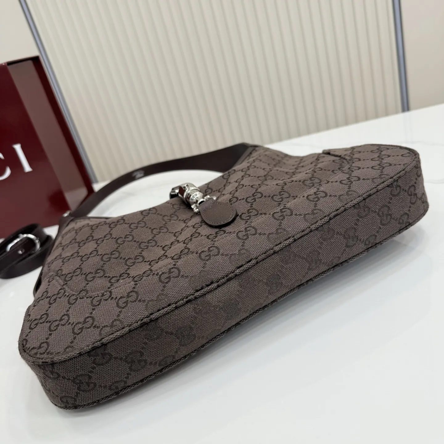 p530。【配全套包装】‼️2026春夏系列全新上市。这款Gucci Jackie 1961系列手袋在《La Famiglia》系列的”La It Girl“造型种呈现。包身选用轻盈但结构挺括的GG帆布,演绎复古灵感的沙色,搭配便于使用的金色调推入式锁扣设计,更添品牌魅力。 深棕色GG帆布 深棕色软皮皮革滚边 银色调配件 深棕色帆布衬里,饰钻石菱格纹图案 内部:1个拉链口袋 可调节提手长度:25 - 29cm 可调节延长肩带高:48 - 61cm 饰推入式锁扣 型号:863136。 尺寸:31.5厘米(宽)x 22厘米(高)x 4.5厘米(深) 重量:约0.35千克 颜色:深棕色/帆布。 意大利创作