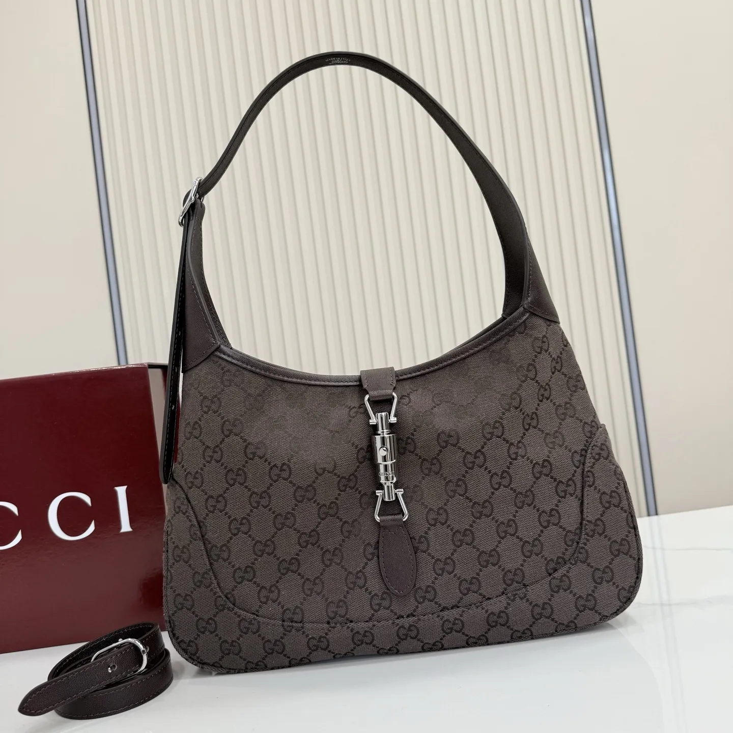p530。【配全套包装】‼️2026春夏系列全新上市。这款Gucci Jackie 1961系列手袋在《La Famiglia》系列的”La It Girl“造型种呈现。包身选用轻盈但结构挺括的GG帆布,演绎复古灵感的沙色,搭配便于使用的金色调推入式锁扣设计,更添品牌魅力。 深棕色GG帆布 深棕色软皮皮革滚边 银色调配件 深棕色帆布衬里,饰钻石菱格纹图案 内部:1个拉链口袋 可调节提手长度:25 - 29cm 可调节延长肩带高:48 - 61cm 饰推入式锁扣 型号:863136。 尺寸:31.5厘米(宽)x 22厘米(高)x 4.5厘米(深) 重量:约0.35千克 颜色:深棕色/帆布。 意大利创作