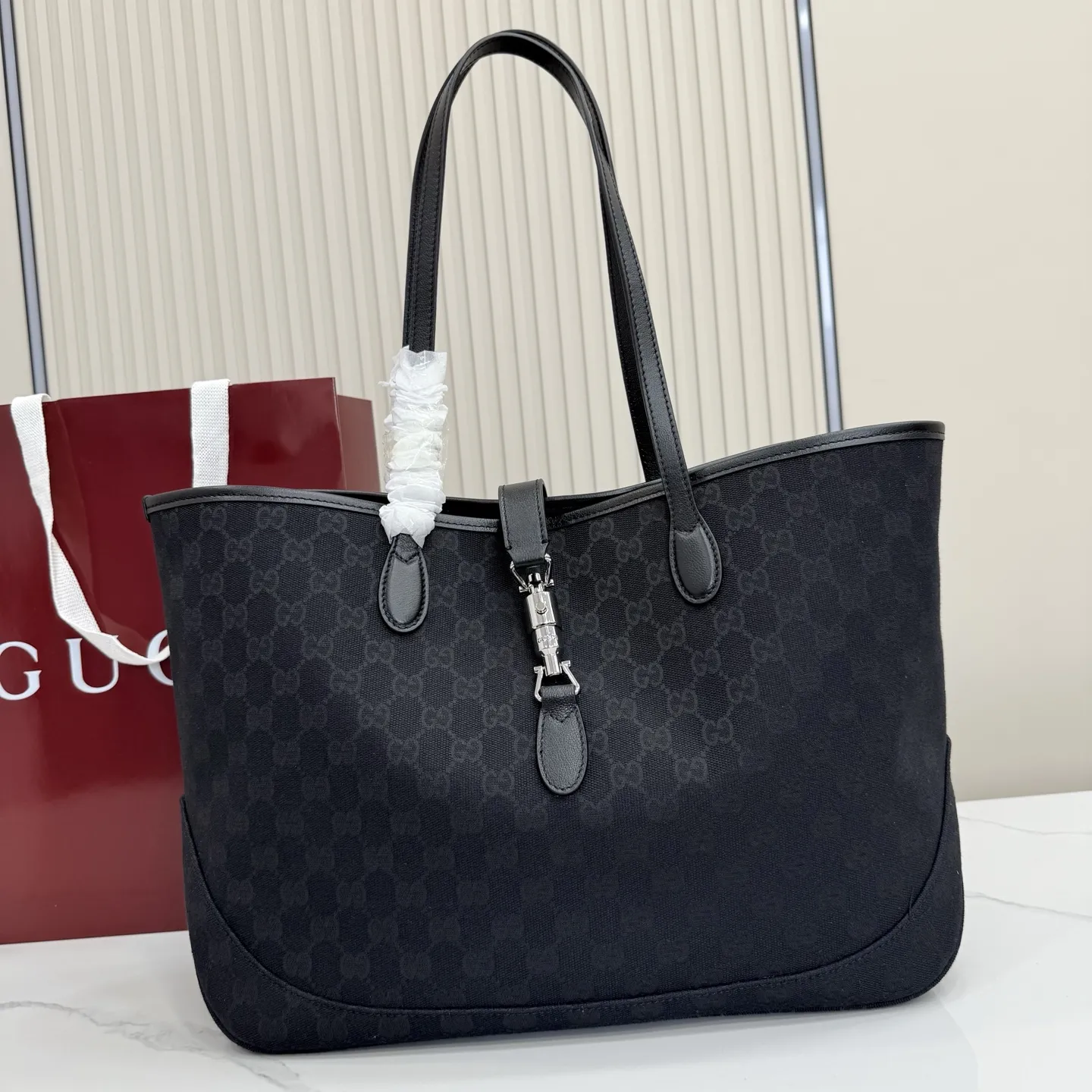 p600。【配全套包装】‼️2026年春夏系列全新上市。这款全新Gucci Jackie系列托特包采用挺括且轻盈的 GG 帆布打造，内衬焕新演绎来自品牌典藏的钻石菱格纹图案。 型号：867015。 尺寸：45厘米（宽）x 28厘米（高）x 12厘米（深） 重量：约0.58千克 颜色：黑皮/黑布。 意大利创作