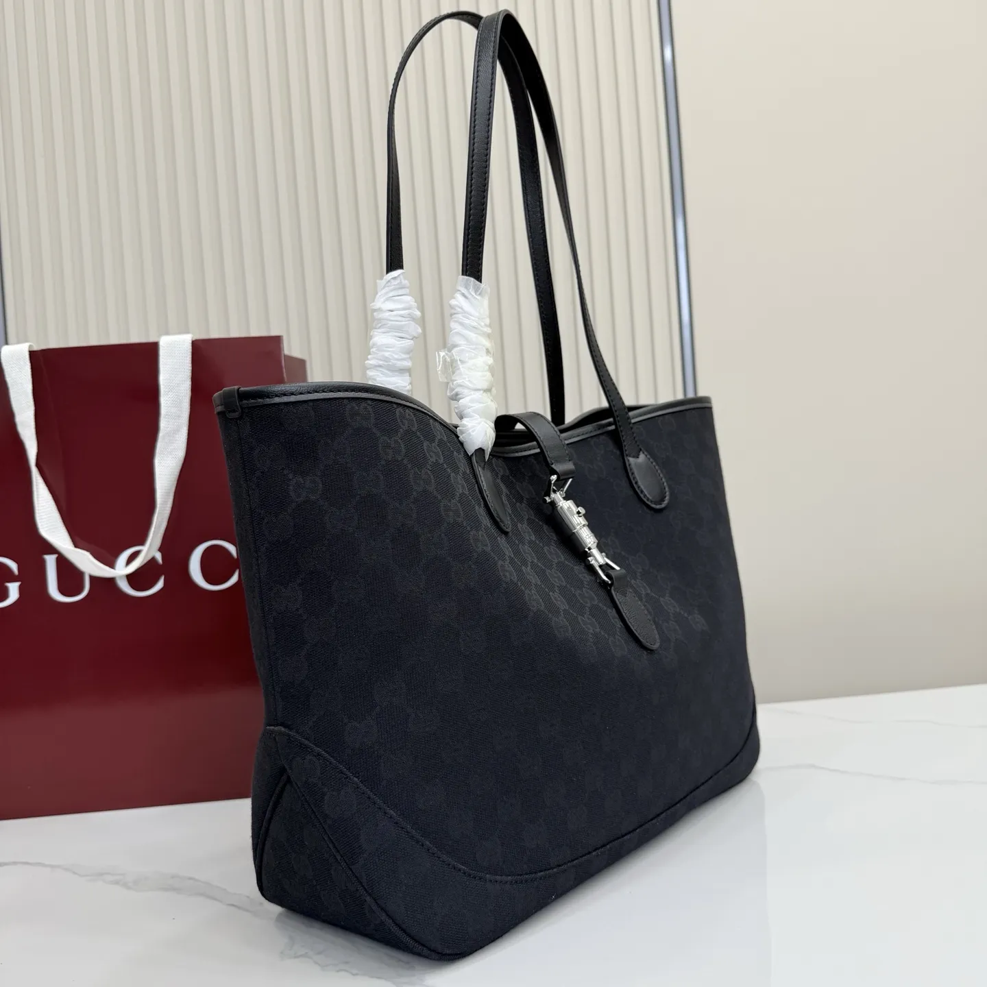 p600。【配全套包装】‼️2026年春夏系列全新上市。这款全新Gucci Jackie系列托特包采用挺括且轻盈的 GG 帆布打造,内衬焕新演绎来自品牌典藏的钻石菱格纹图案。 型号:867015。 尺寸:45厘米(宽)x 28厘米(高)x 12厘米(深) 重量:约0.58千克 颜色:黑皮/黑布。 意大利创作