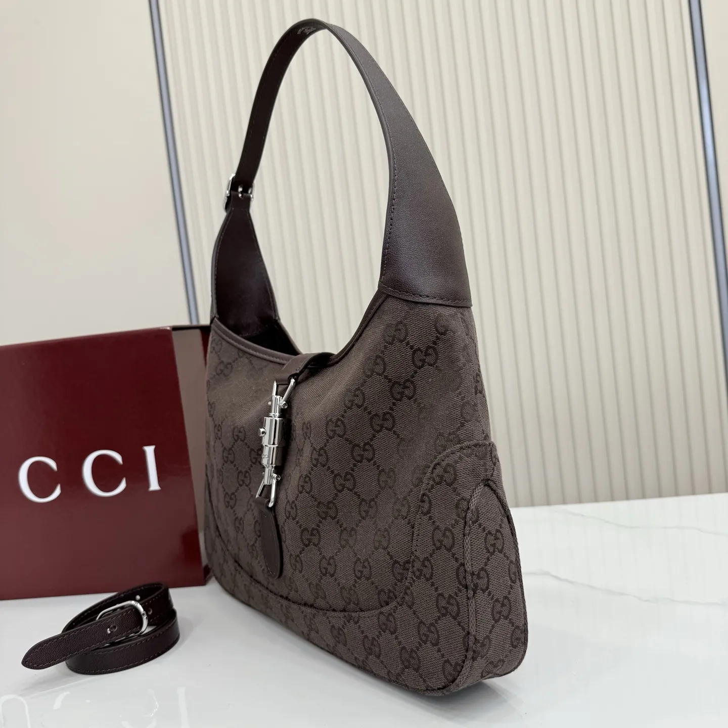 p530。【配全套包装】‼️2026春夏系列全新上市。这款Gucci Jackie 1961系列手袋在《La Famiglia》系列的&rdquo;La It Girl&ldquo;造型种呈现。包身选用轻盈但结构挺括的GG帆布，演绎复古灵感的沙色，搭配便于使用的金色调推入式锁扣设计，更添品牌魅力。 深棕色GG帆布 深棕色软皮皮革滚边 银色调配件 深棕色帆布衬里，饰钻石菱格纹图案 内部：1个拉链口袋 可调节提手长度：25 - 29cm 可调节延长肩带高：48 - 61cm 饰推入式锁扣 型号：863136。 尺寸：31.5厘米（宽）x 22厘米（高）x 4.5厘米（深） 重量：约0.35千克 颜色：深棕色/帆布。 意大利创作