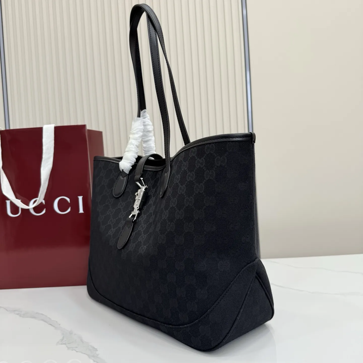 p600。【配全套包装】‼️2026年春夏系列全新上市。这款全新Gucci Jackie系列托特包采用挺括且轻盈的 GG 帆布打造，内衬焕新演绎来自品牌典藏的钻石菱格纹图案。 型号：867015。 尺寸：45厘米（宽）x 28厘米（高）x 12厘米（深） 重量：约0.58千克 颜色：黑皮/黑布。 意大利创作