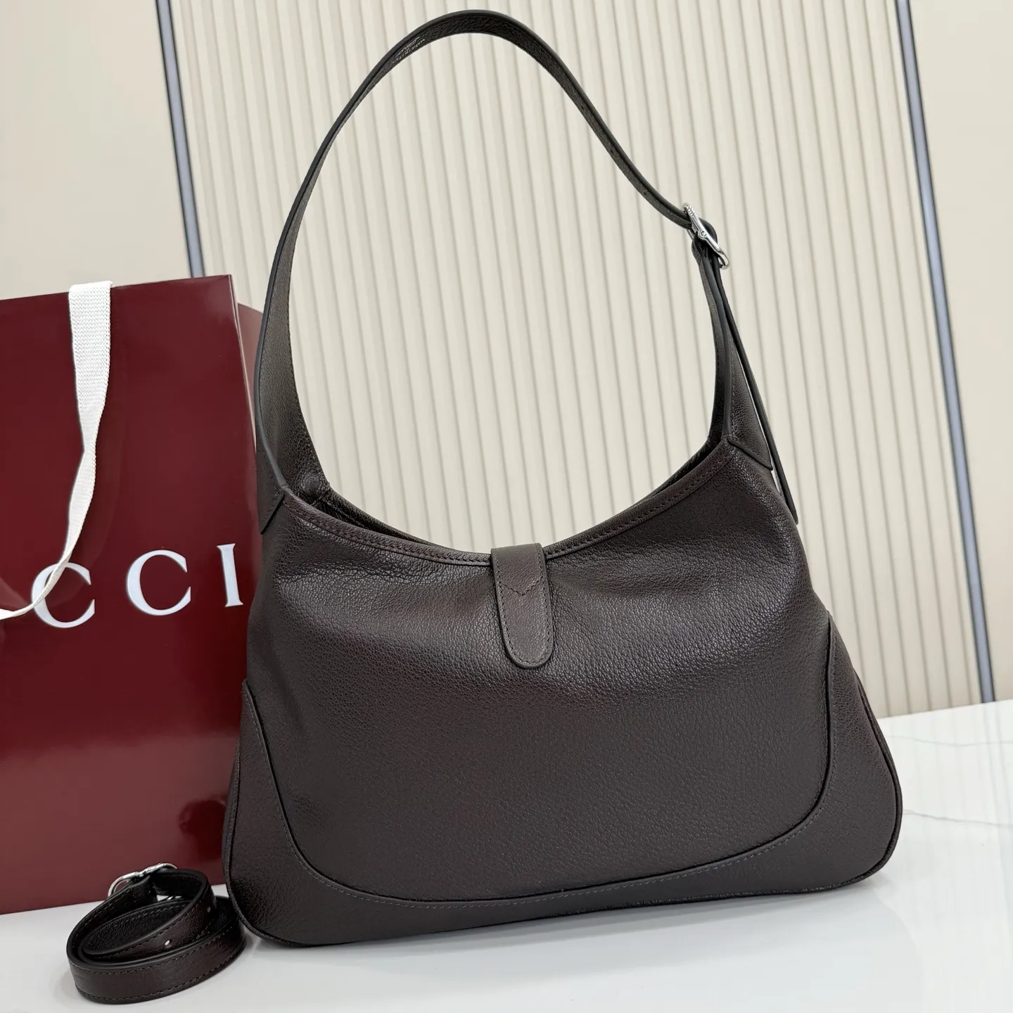 p750。【配全套包装】‼️(羊皮)2026春夏系列全新上市。这款Gucci Jackie 9161系列手袋呈现时髦风格,选用柔软粒面羊皮革,经手工悉心做旧处理,呈现出复古质感。手袋搭配便于使用的推入式锁扣设计,金色调金属配件更添品牌标志性五金细节的风格魅力。 型号:863136。 尺寸:31.5厘米(宽)x 22厘米(高)x 4.5厘米(深) 重量:约0.35千克 颜色:深棕色/羊皮。