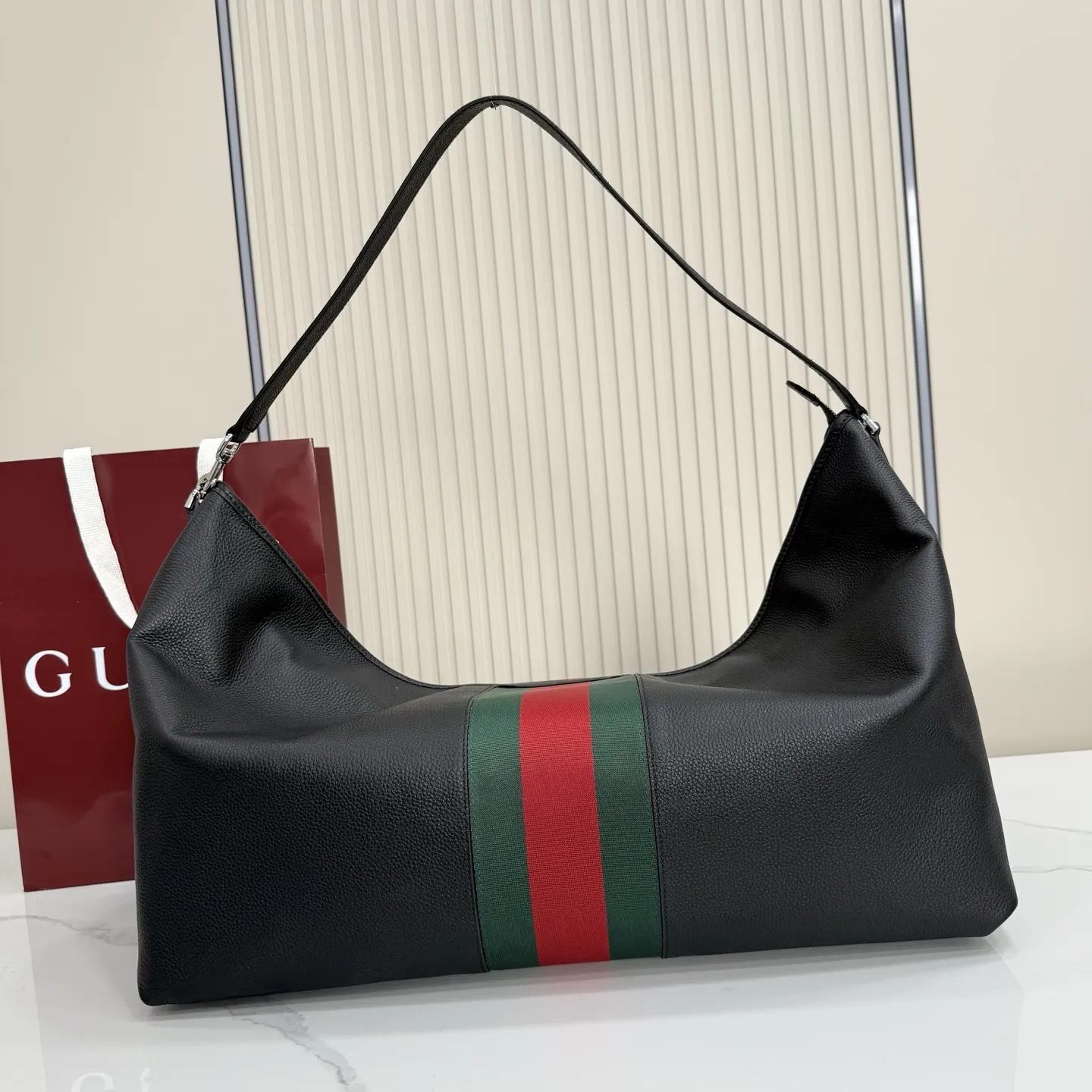p800。【配全套包装】‼️Gucci Primavera系列通过融合创新与务实的愿景,确立了廓形、质地与材质的新语汇。加宽的织带嵌花细节以现代态度重塑包袋廓形。柔软的哑光皮革饰有低调的“Gucci Made in Italy”标识,多用途肩带适合日常出行背携。 黑色软皮,哑光表面 钯色金属配件 黑色针织衬里 织带嵌花和银色烫银“Gucci 意大利创作”标识 内部:1个拉链口袋 手柄垂直长度:30厘米 可拆卸和可调节皮革肩带,下垂长度65厘米,长度:100-120厘米 拉链开合 型号:A006KP。 尺寸:65厘米(宽)x20厘米(高)x37厘米(深) 重量:约1.430千克 颜色:黑色全皮。 意大利创作