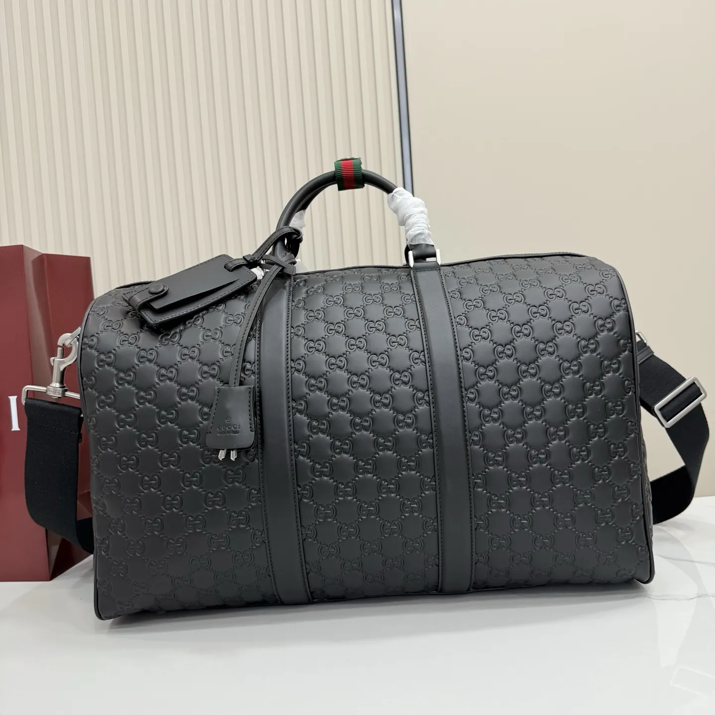 p980。‼️GG Emblem系列以饰GG印花压纹图案光面皮革 焕新演绎品牌历久弥新的优雅风范和精湛工艺。这款旅行包采用缀饰织带细节的按扣开合设计,方便固定双提手。 黑色GG印花压纹光面皮革 黑色皮革滚边 黑色棉麻混纺衬里 饰织带细节按扣开合 内部:1个拉链袋 外部:一个可拆卸身份标牌和钥匙扣 提手高:12厘米 可拆卸可调节帆布肩带(高度:125厘米 - 130厘米) 拉链开合 型号:850220。 尺寸:45厘米(宽)x 29厘米(高)x 25厘米(深) 重量:约2.1千克 颜色:黑色/压花。