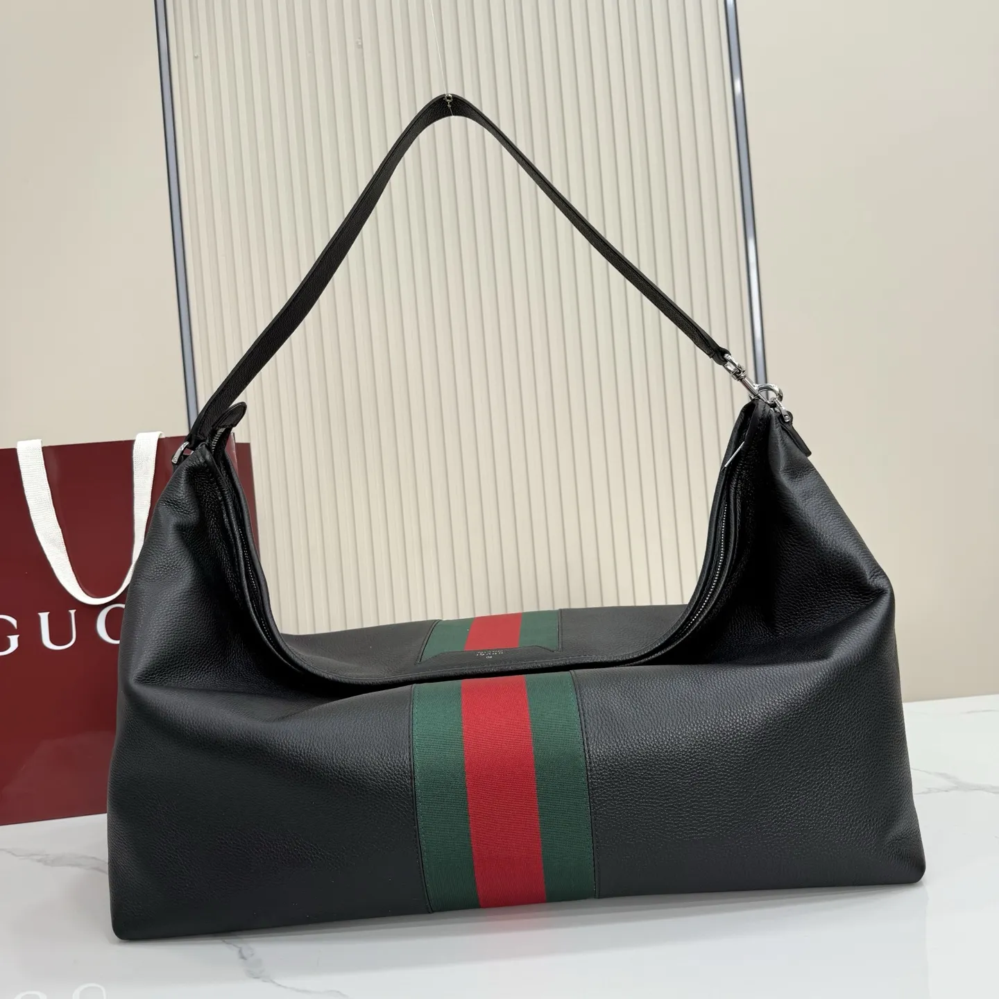 p800。【配全套包装】‼️Gucci Primavera系列通过融合创新与务实的愿景,确立了廓形、质地与材质的新语汇。加宽的织带嵌花细节以现代态度重塑包袋廓形。柔软的哑光皮革饰有低调的“Gucci Made in Italy”标识,多用途肩带适合日常出行背携。 黑色软皮,哑光表面 钯色金属配件 黑色针织衬里 织带嵌花和银色烫银“Gucci 意大利创作”标识 内部:1个拉链口袋 手柄垂直长度:30厘米 可拆卸和可调节皮革肩带,下垂长度65厘米,长度:100-120厘米 拉链开合 型号:A006KP。 尺寸:65厘米(宽)x20厘米(高)x37厘米(深) 重量:约1.430千克 颜色:黑色全皮。 意大利创作