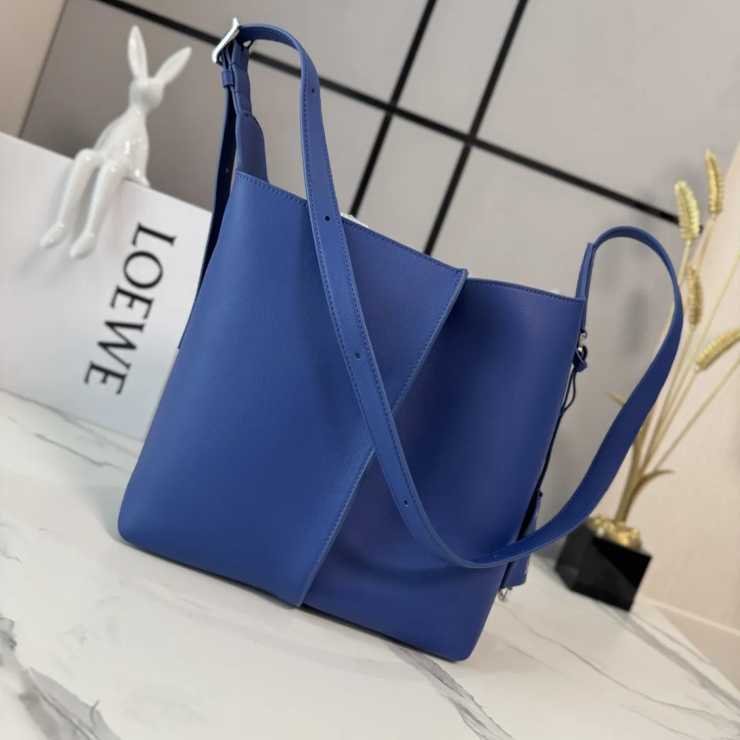 LO℮w℮🌟中号光滑Bilbao梯形水桶包 呈现简约几何设计。采用皮革拼接打造，中央饰有褶皱，造型柔软贴身，是日常随身携带的理想选择。此中号版本采用光滑牛皮革制成。*🉑肩背或斜挎*🉑调节肩带*🉑拆卸Double L压纹皮革钟形挂饰，内藏实用开瓶器*额外的外部D形环，可用于搭配个性化挂饰*钩扣🉑固定随身物品 绒面革衬里*LOE*WE烫银. size:13*25*24CM 型号：652604 F：780