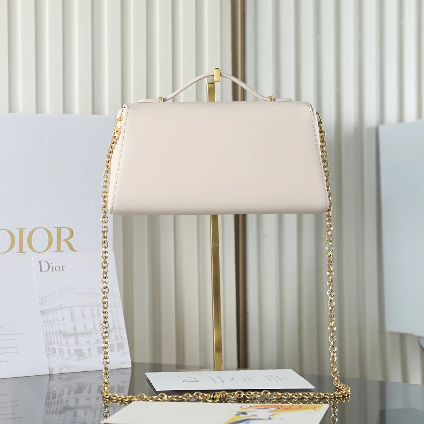 P700 原厂级 M&eacute;daillon 手拿包\n\n这款 Dior M&eacute;daillon 手拿包设计百搭，彰显 Dior 经久不衰的优雅风范。Dior M&eacute;daillon 标志扣环呼应 Dior 沙龙 18 世纪洛可可风格的优雅格调，缝有三角形衬料的挺括廓形则突显时髦气息。设有顶部手柄和可调节、可拆卸的链条，可手提或肩背突显高雅气质，可与日常造型或晚装搭配。\n\nM3671\n尺寸：26 x 11.5 x 4.5 厘米（长 x 高 x 宽）